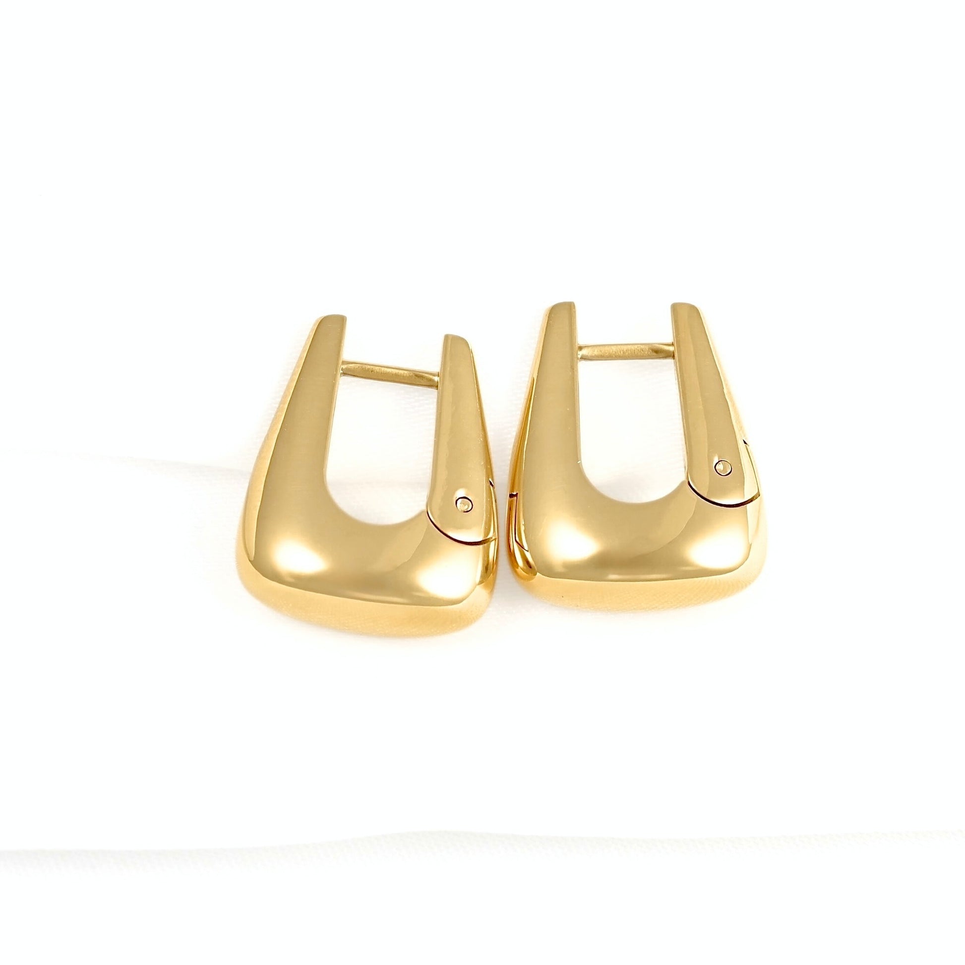 A pair of gold-toned, geometric hoop earrings with a  smooth polished finish, displayed on a clean white background.