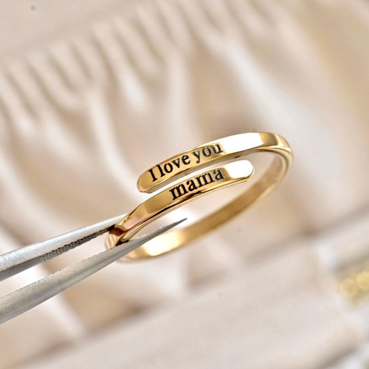 Gold ring with 'I love you mama' engraving on a soft beige background
