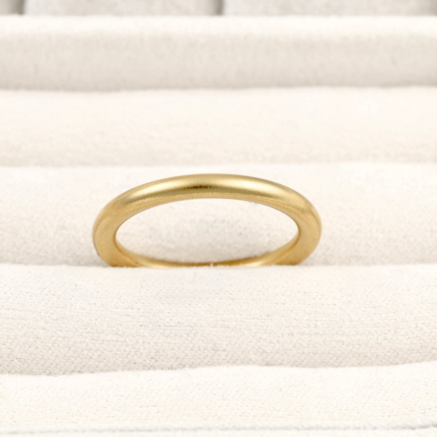 Thin gold band in a beige ring tray