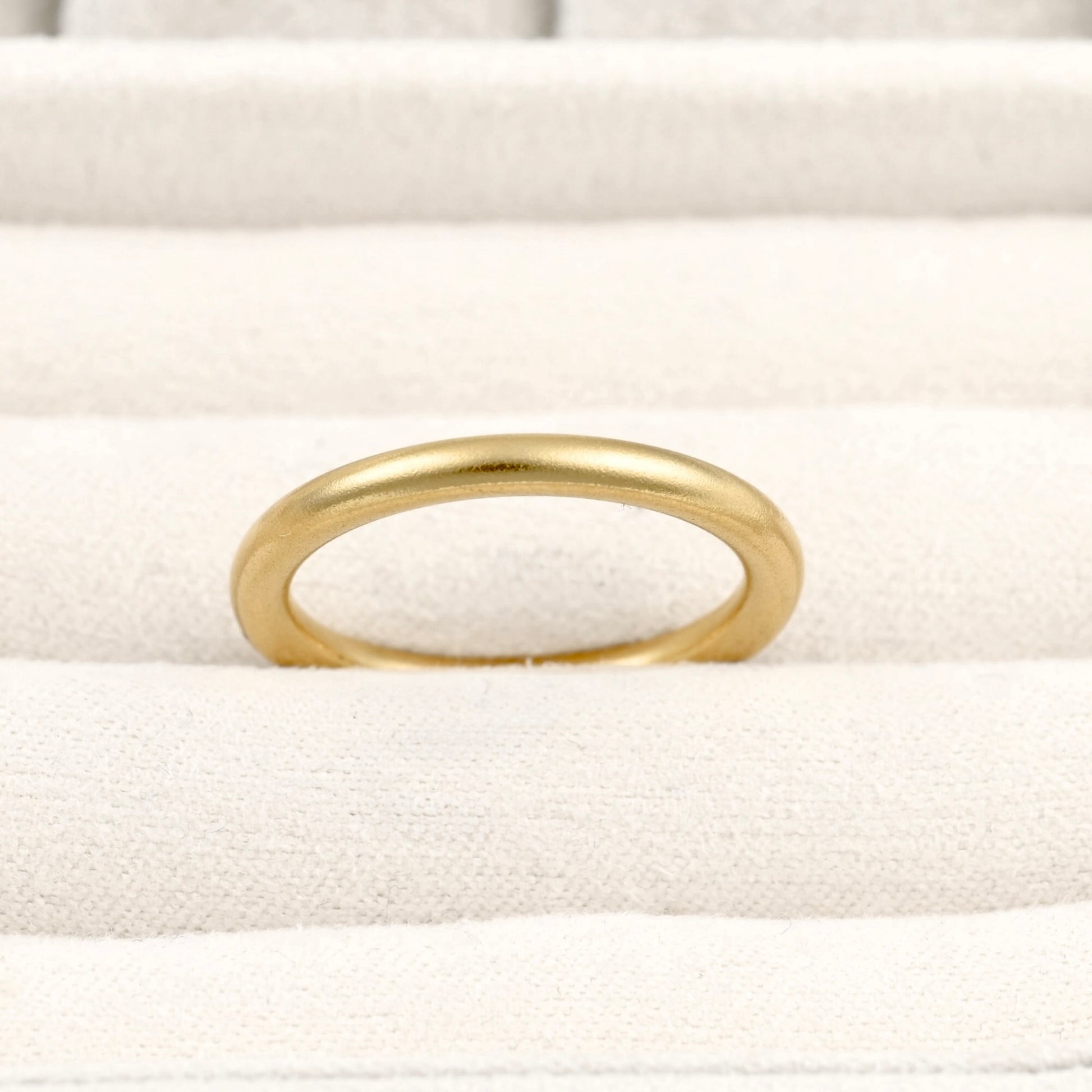 Thin gold band in a beige ring tray