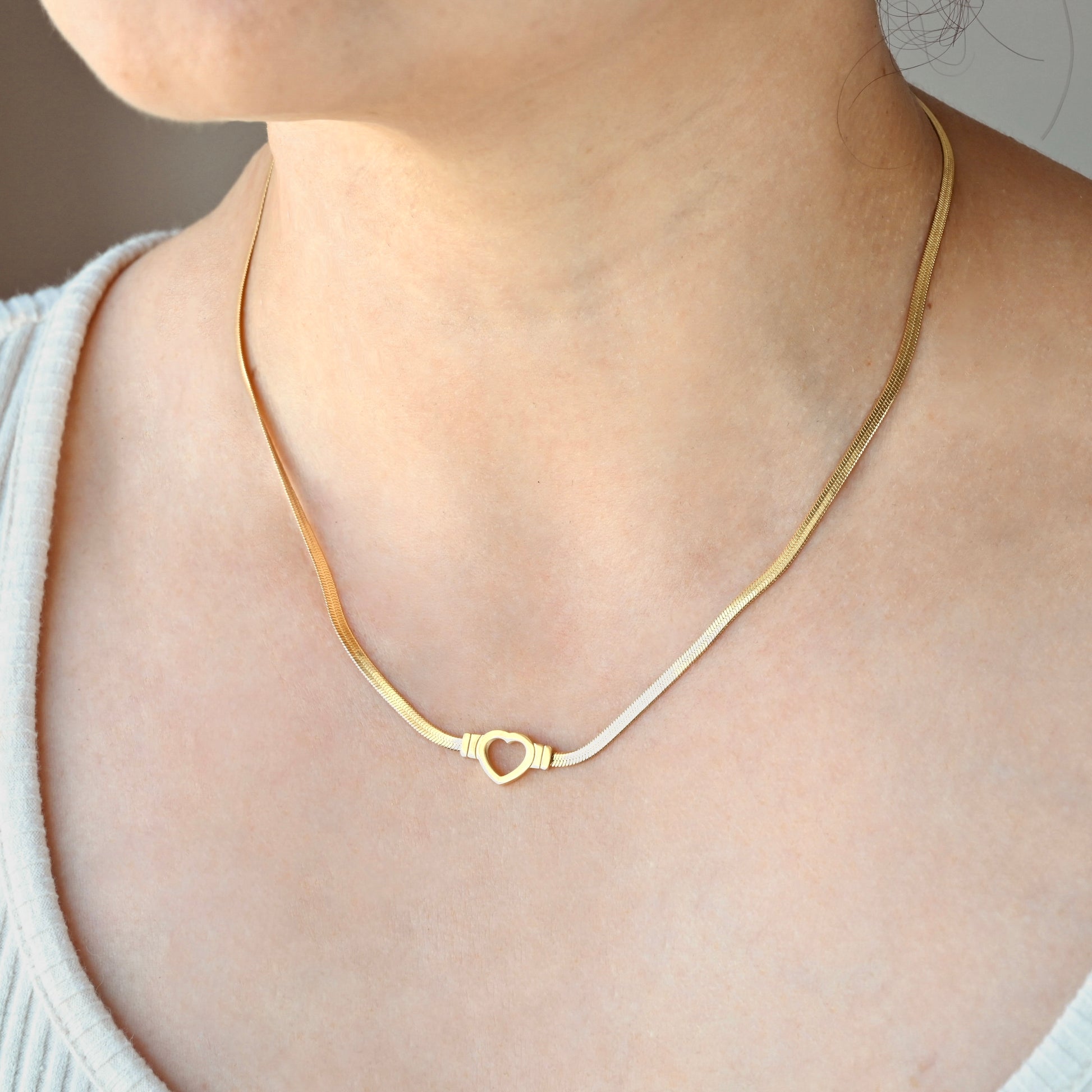 Gold necklace with a heart clasp worn by a person