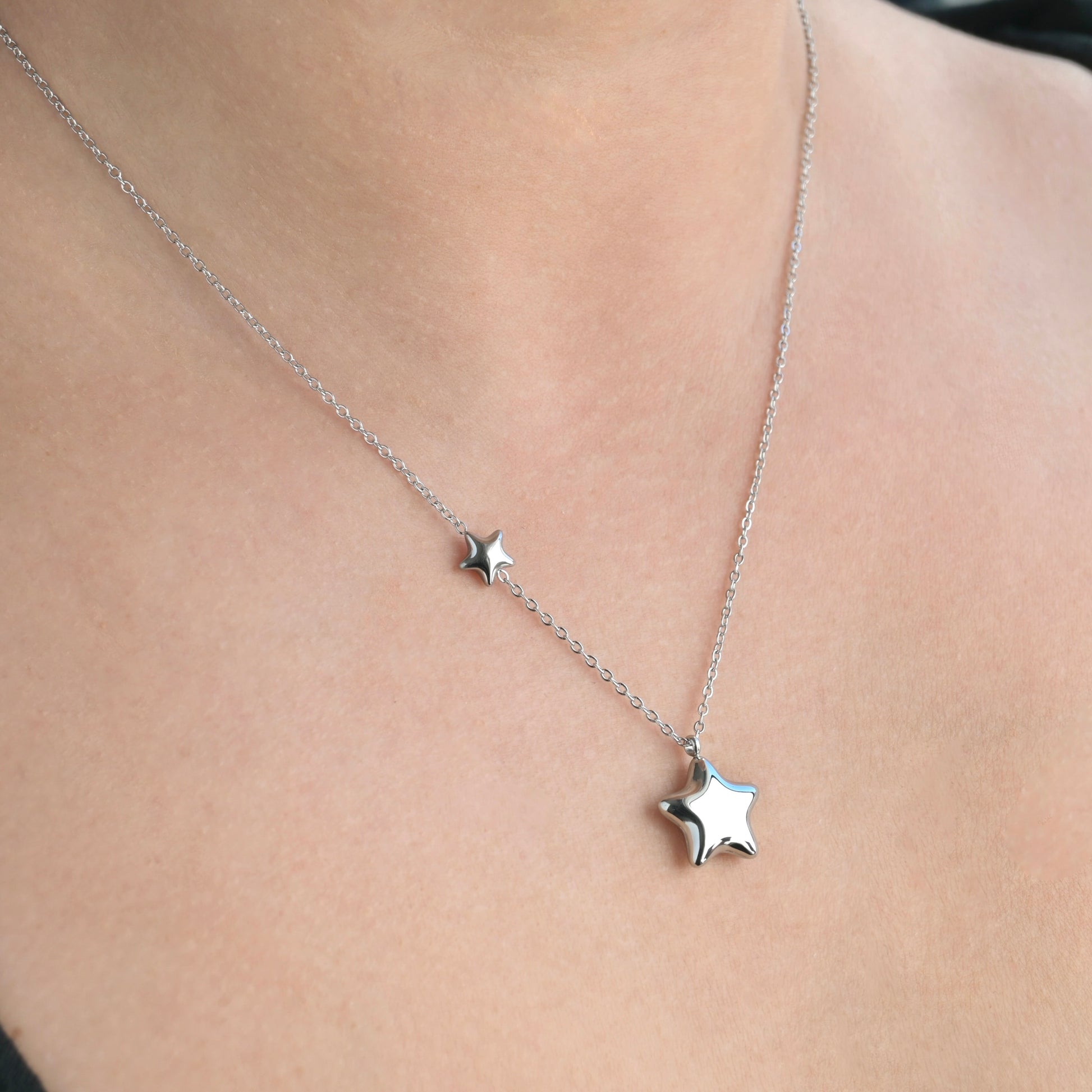 Silver  asymmetrical star necklace on a person's neck