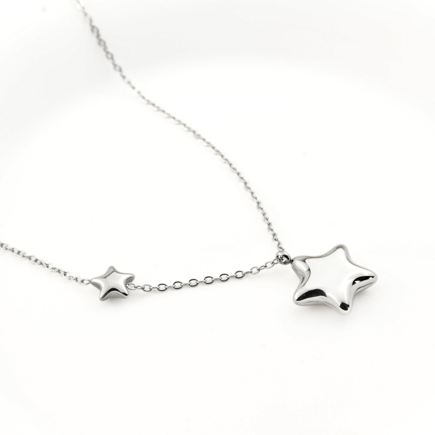 Silver puffy double star pendant on a white background