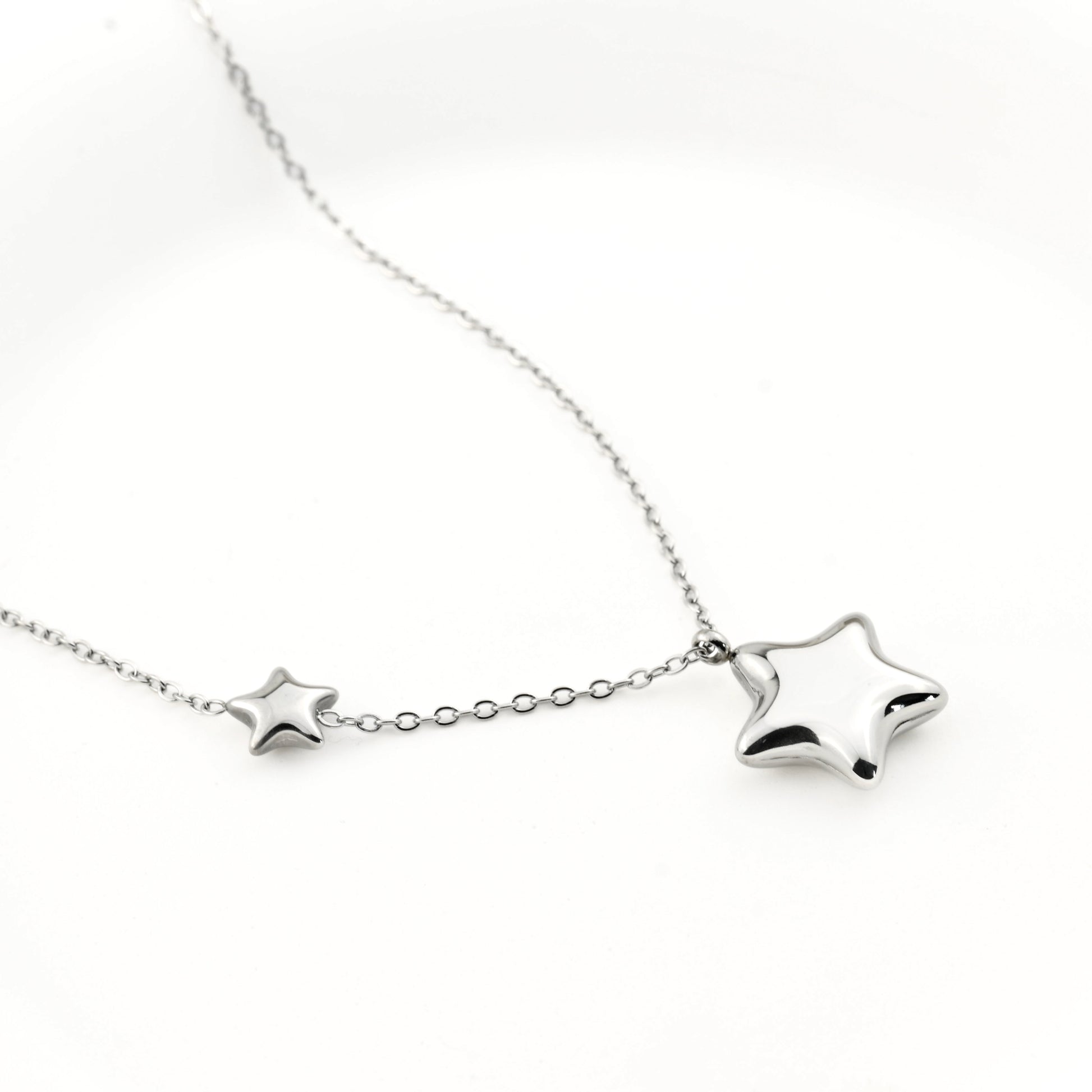 Silver puffy double star pendant on a white background