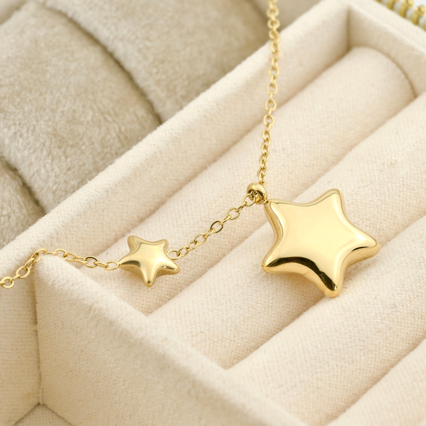 Gold celestial necklace on a beige jewelry box