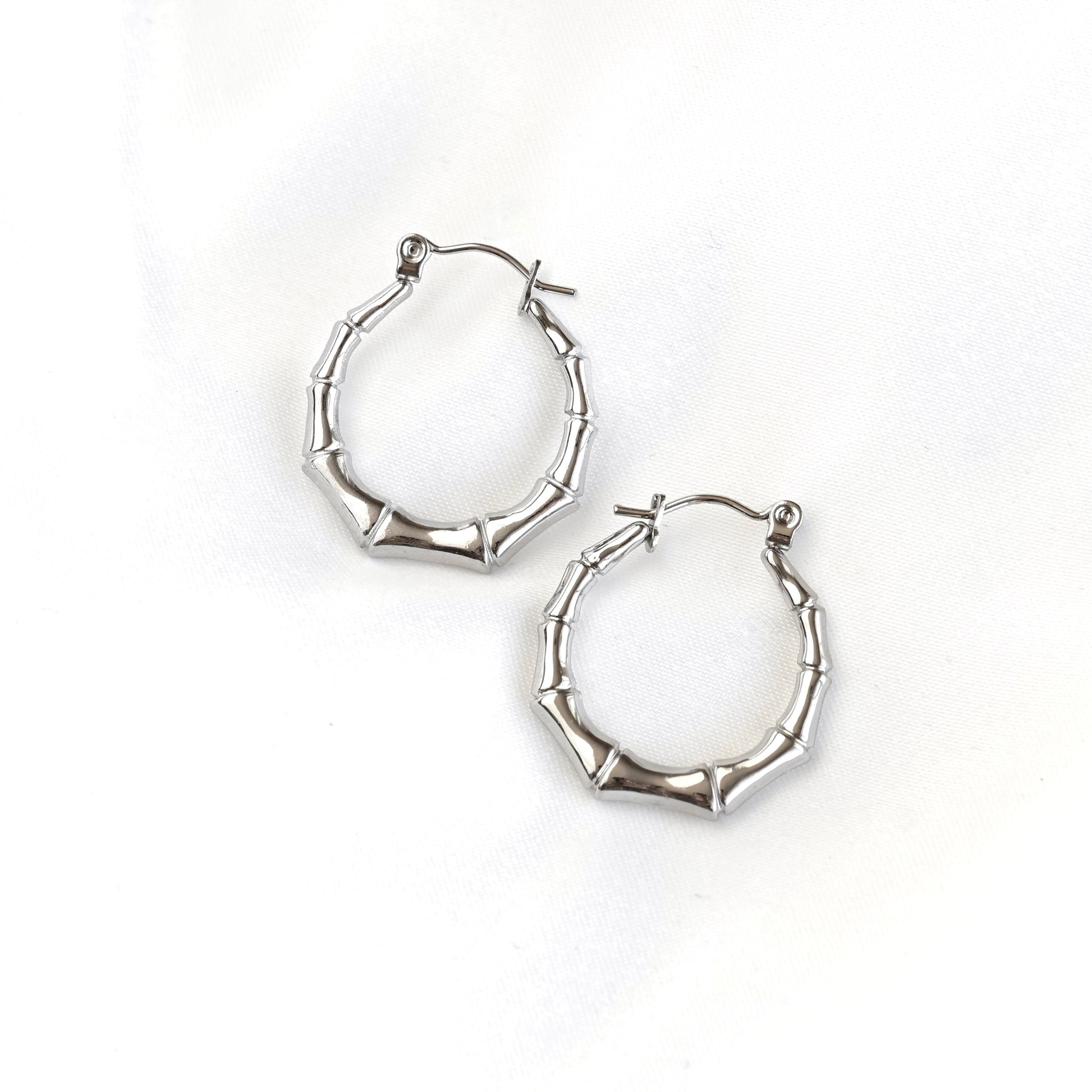 A pair of silver hoop earrings with a textured, segmented design resembling bamboo stalks, displayed on a clean white background.