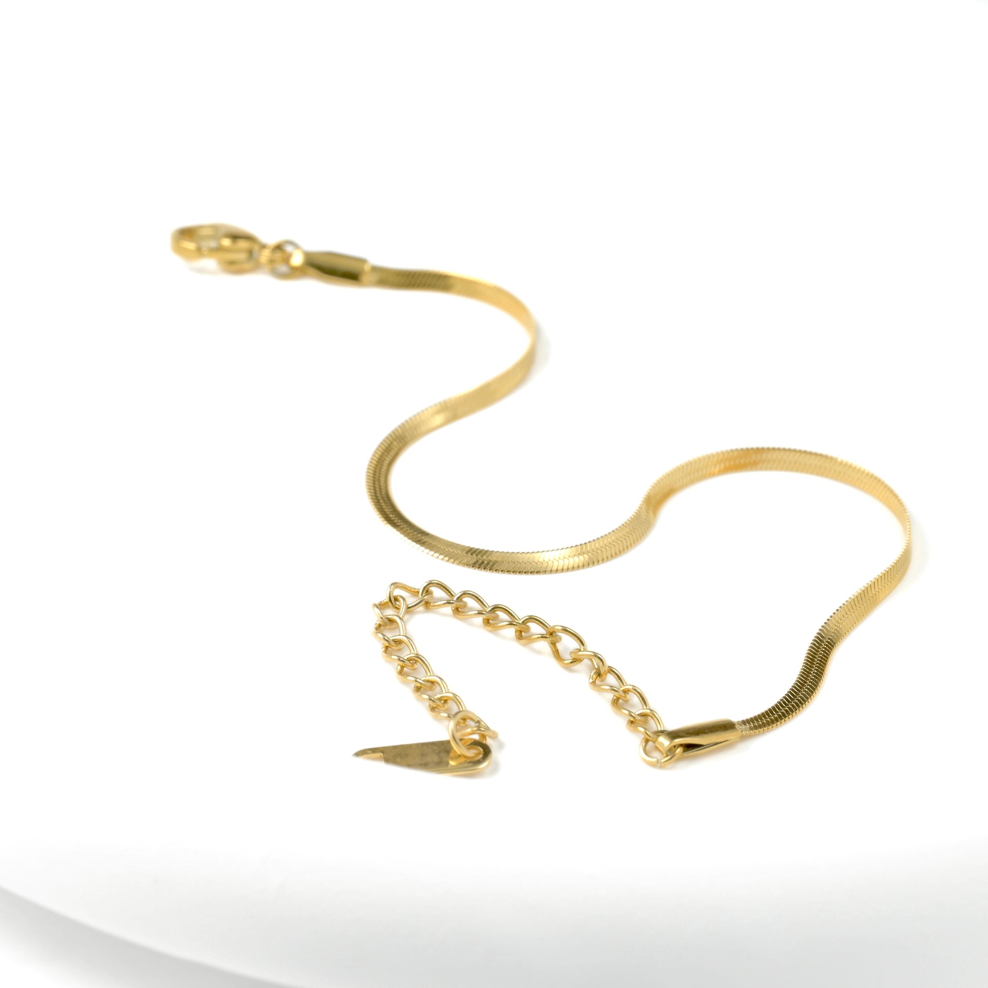 2mm flat herringbone bracelet with a lobster claw clasp and extender on a white background
