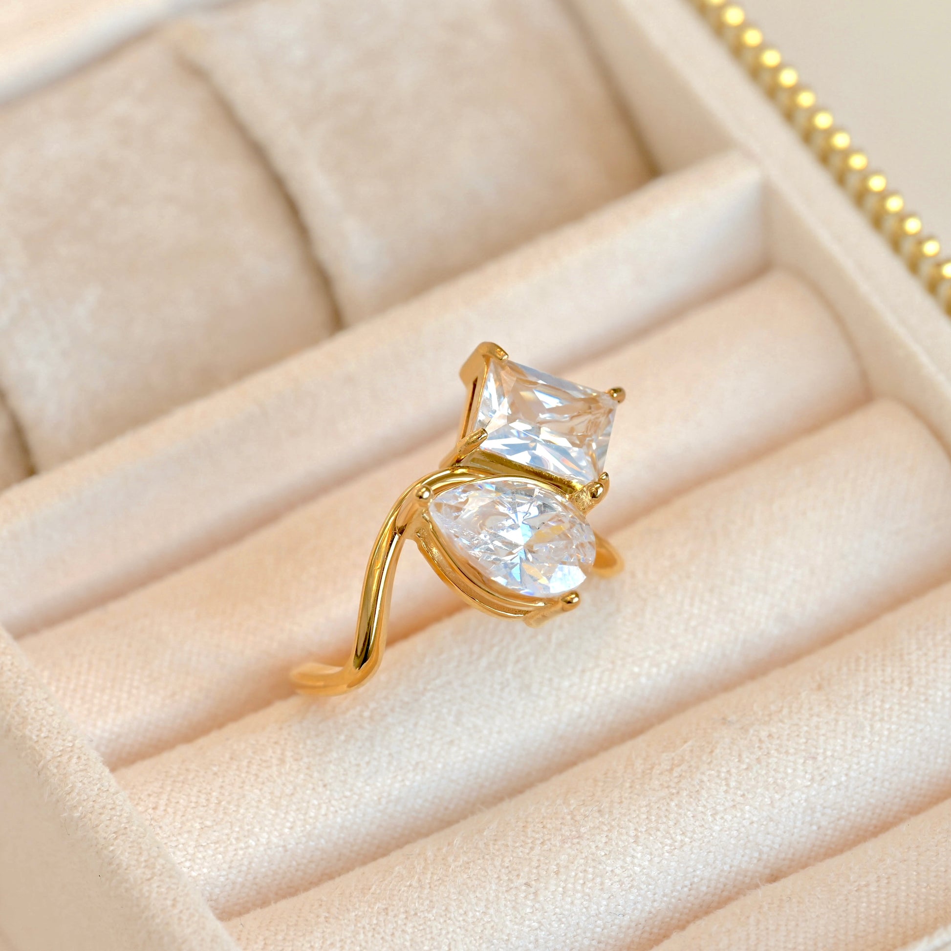Gold ring with two large clear CZ stones in a beige jewelry box