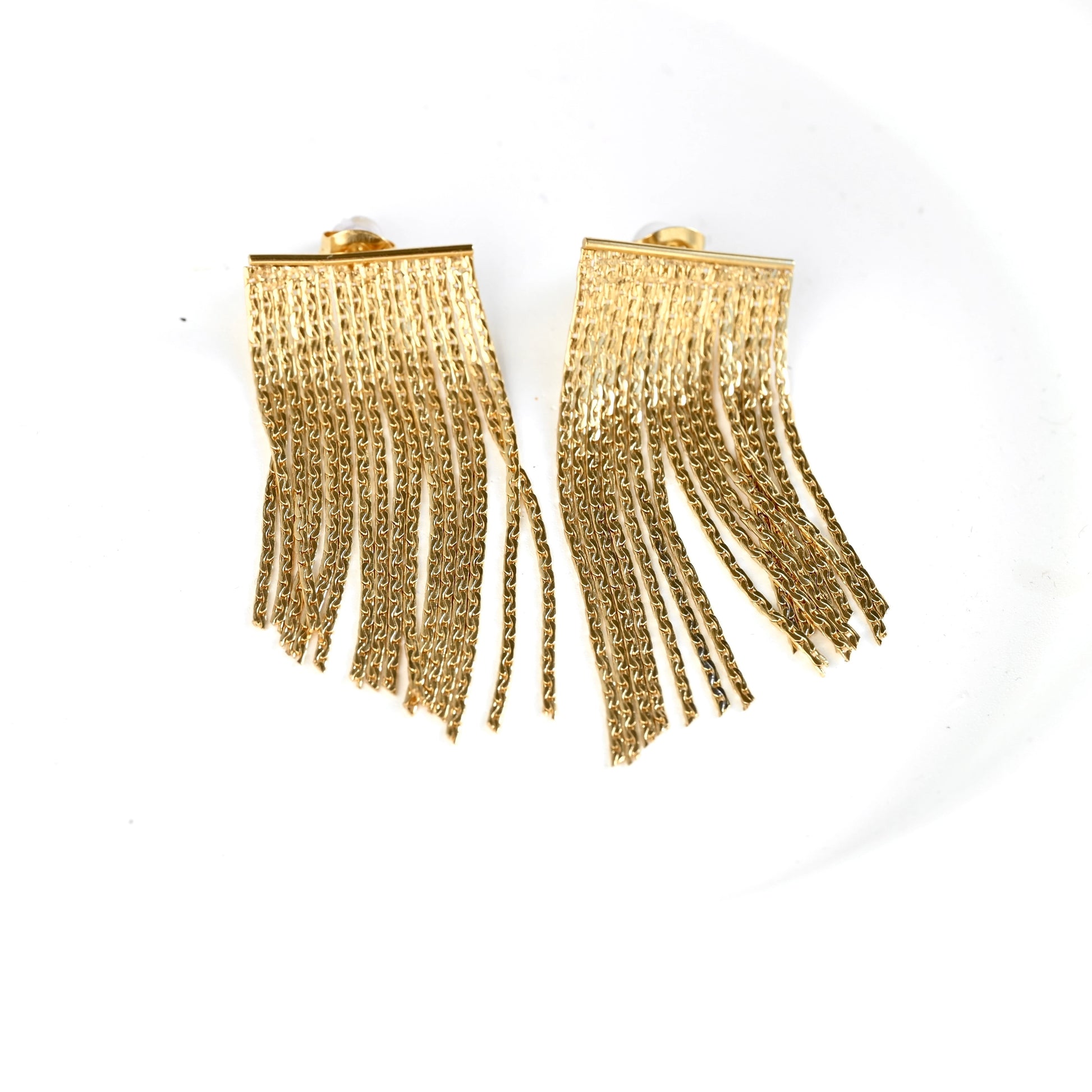 A pair of gold tassel earrings with a textured rectangular top and dangling chain-like fringe, shown on a plain white background.