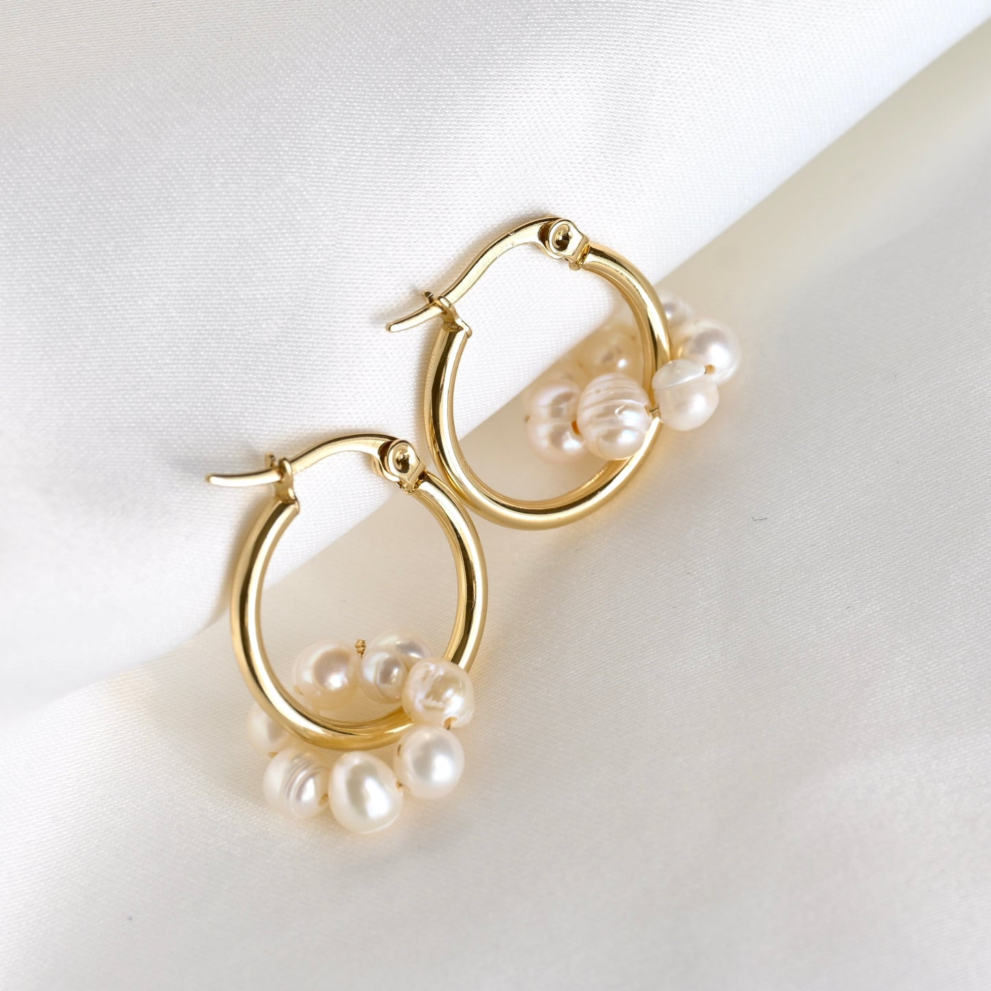 Dainty gold hoops with  freshwater pearls on a light background