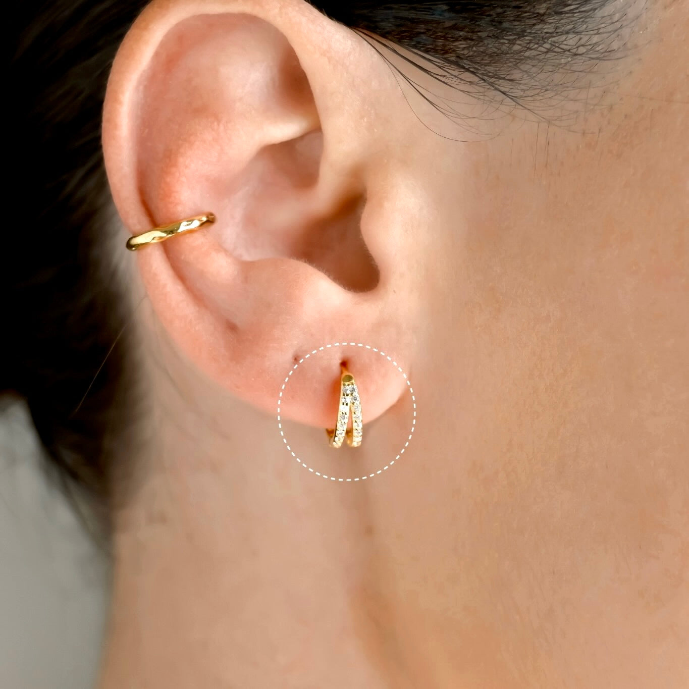 Close-up of an ear wearing a gold hoop earring with pave CZ stones