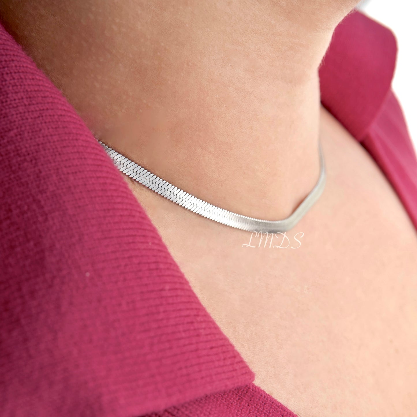 Side view of silver herringbone necklace on a person wearing a pink top with LMDS watermark in the middle