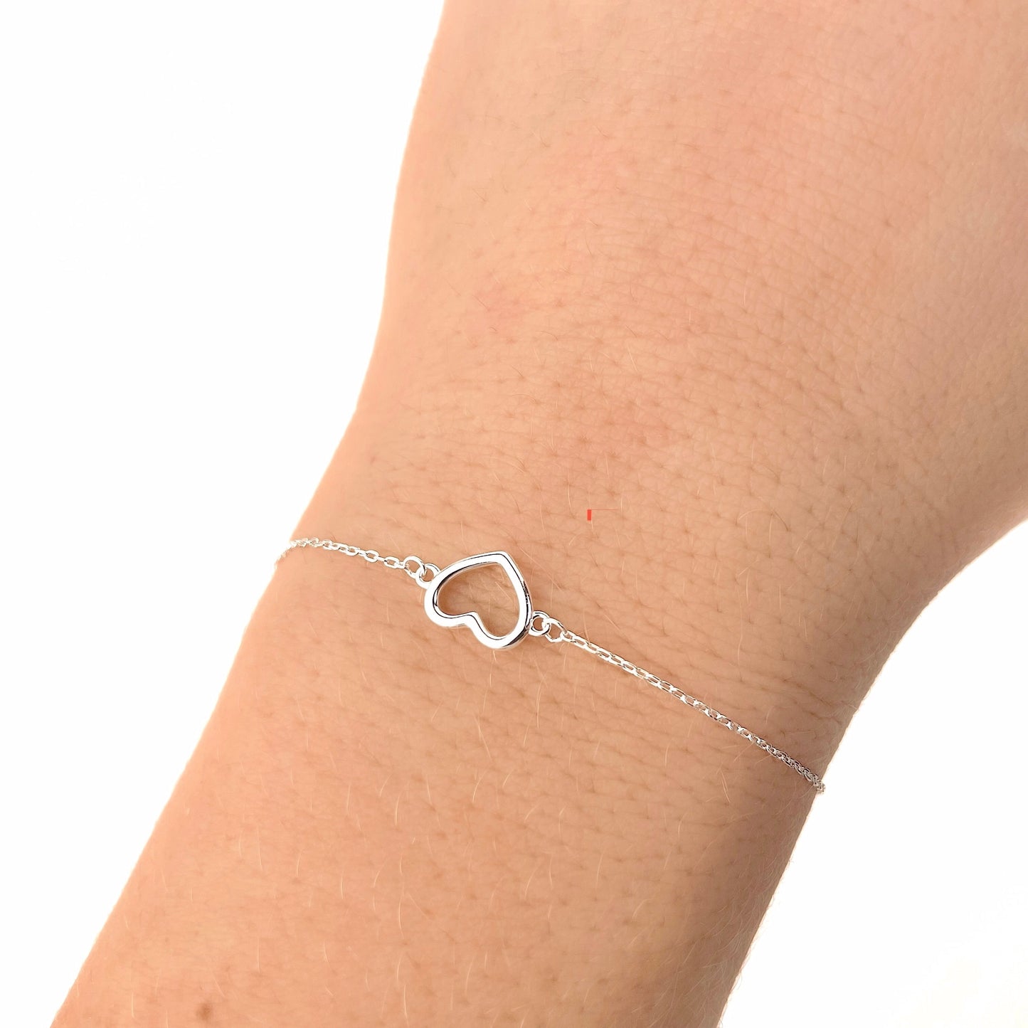 Silver heart-shaped bracelet on a wrist against a white background