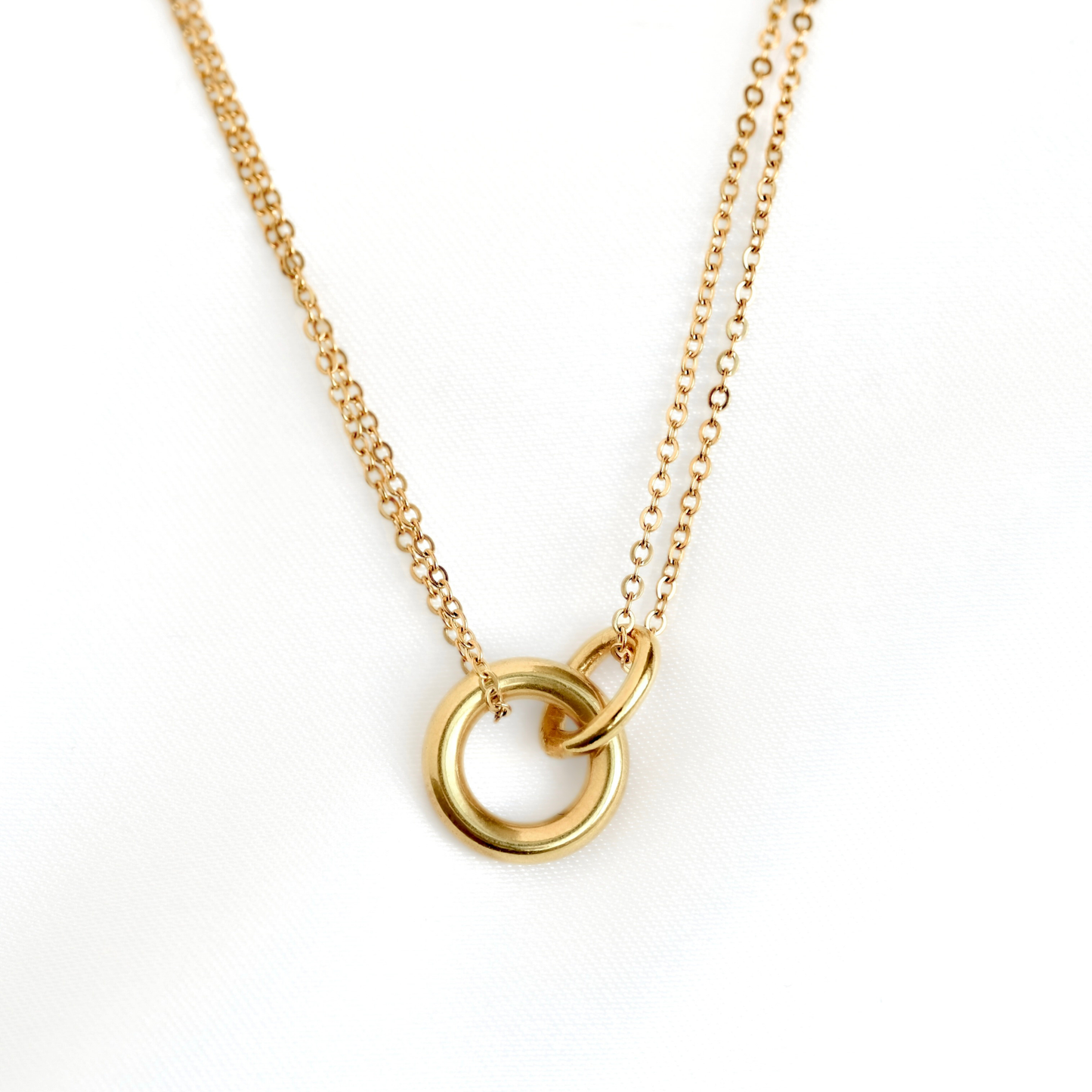 A layered  gold chain necklace featuring two interlocking open circular rings, photographed against a clean white background.