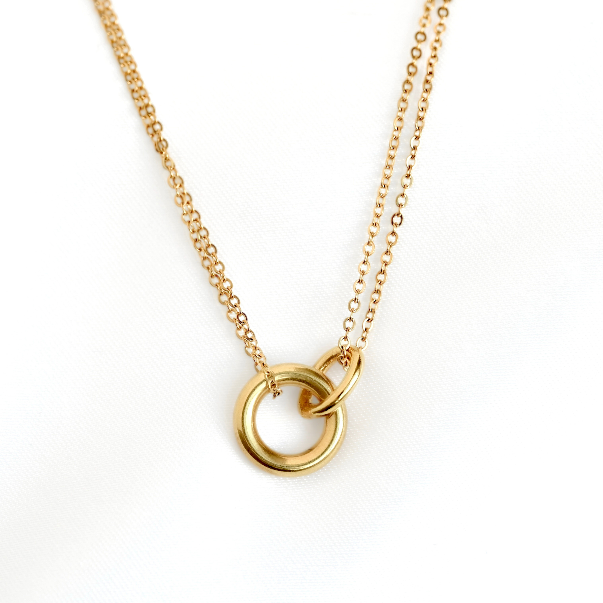 A layered  gold chain necklace featuring two interlocking open circular rings, photographed against a clean white background.