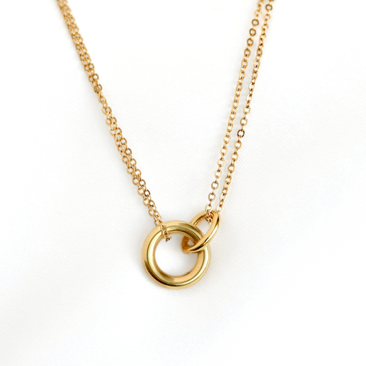 A layered  gold chain necklace featuring two interlocking open circular rings, photographed against a clean white background.