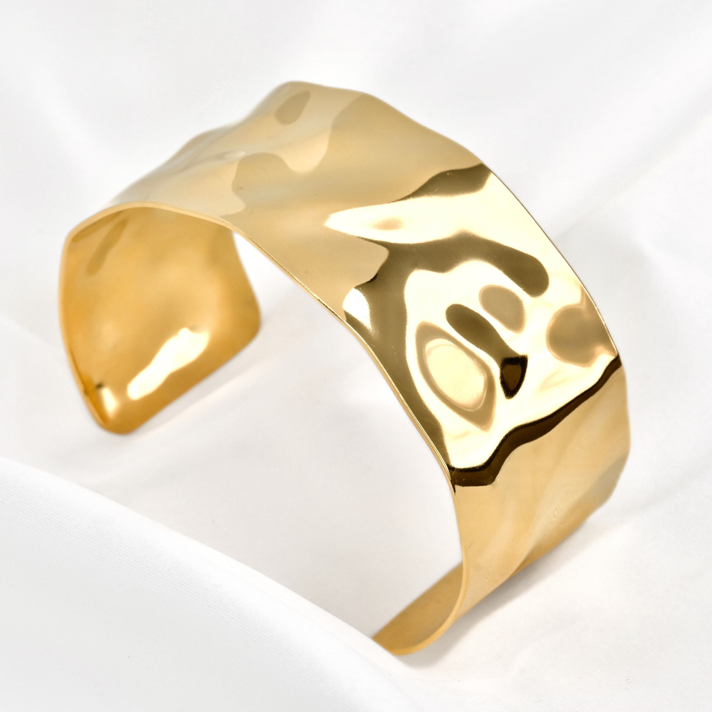 Wide hammered cuff bracelet with a textured surface on a white background