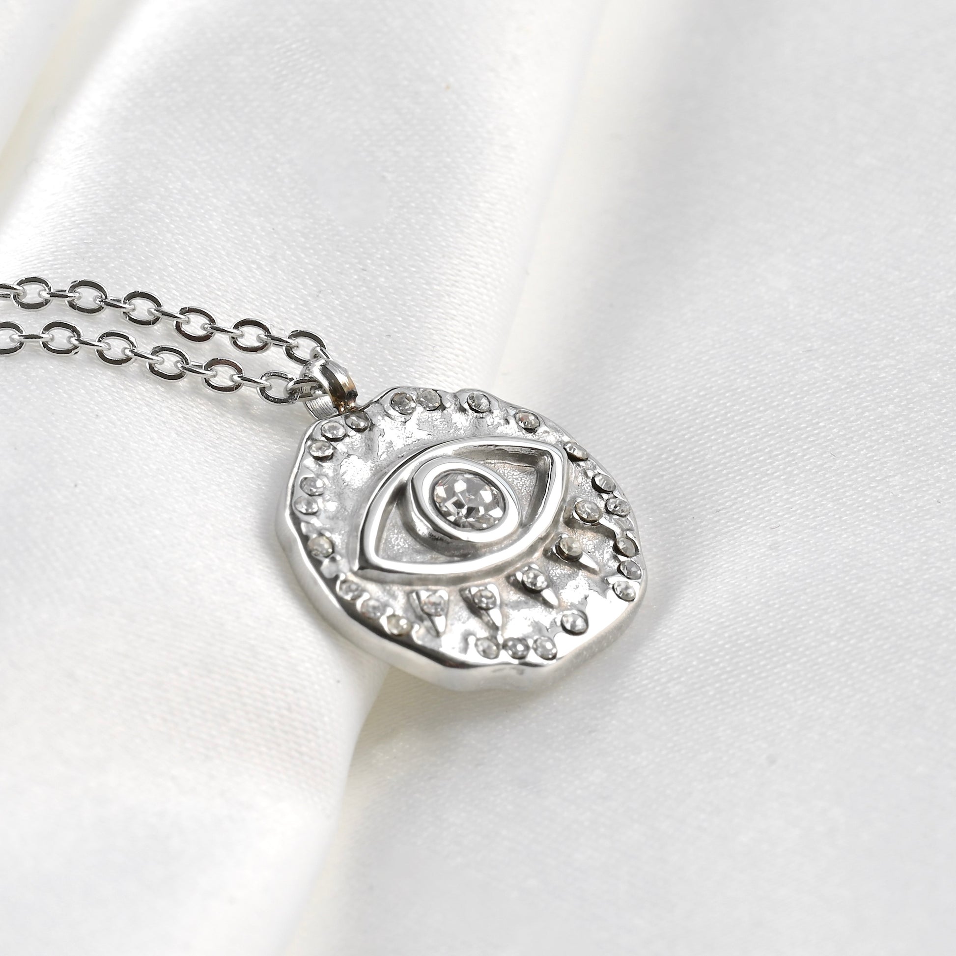 Silver coin necklace with an eye-shaped pendant on a white background