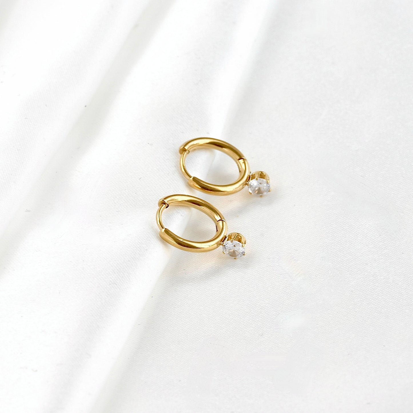 Wide angle view of cubic zirconia attached gold hoop earrings on a white background