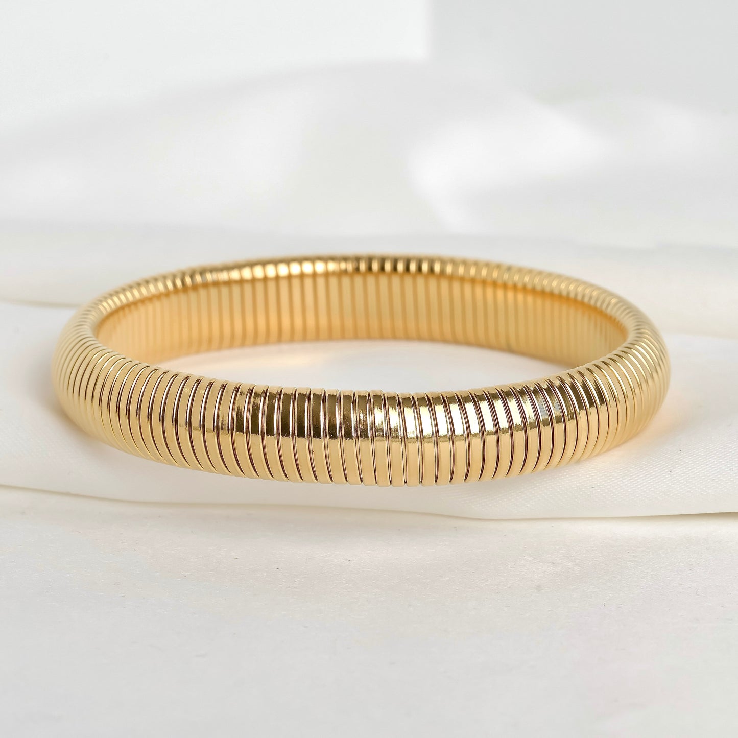 Gold ribbed stretch bangle on a white background