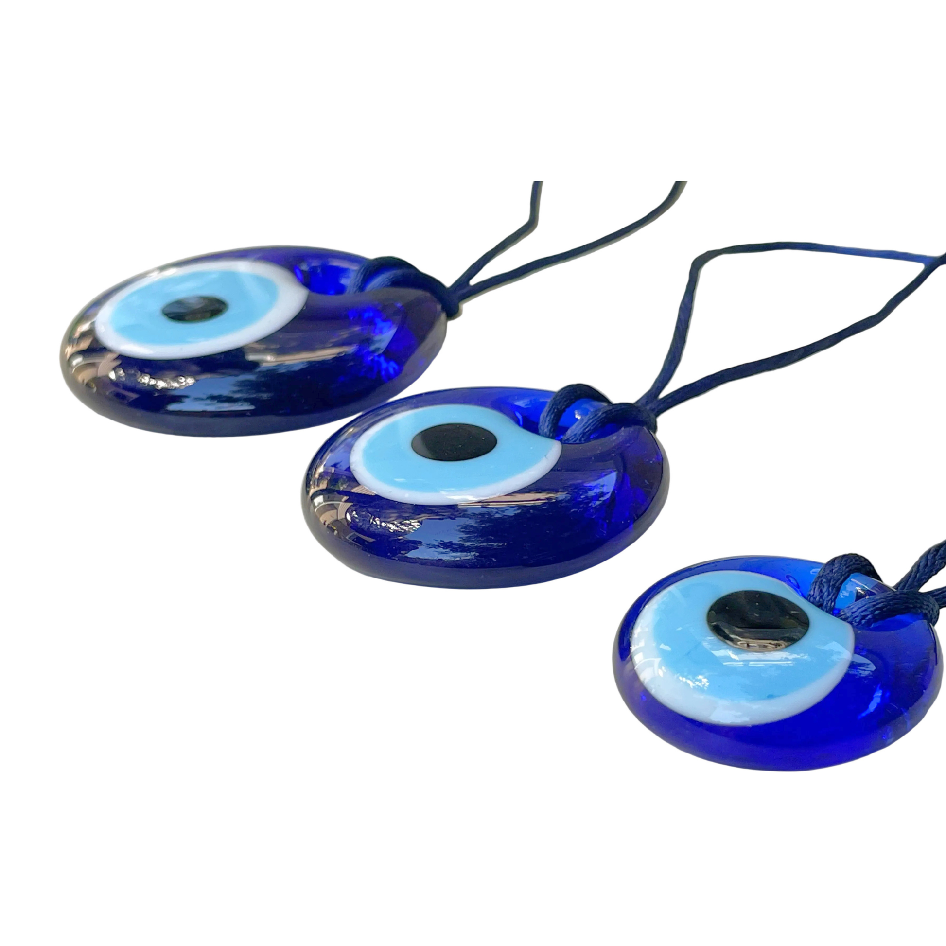 Three blue evil eye charms on navy strings against a white background