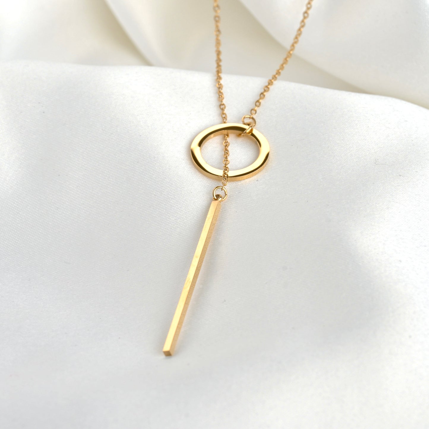 Front view of gold Y necklace with a circle  and bar pendant on a white background
