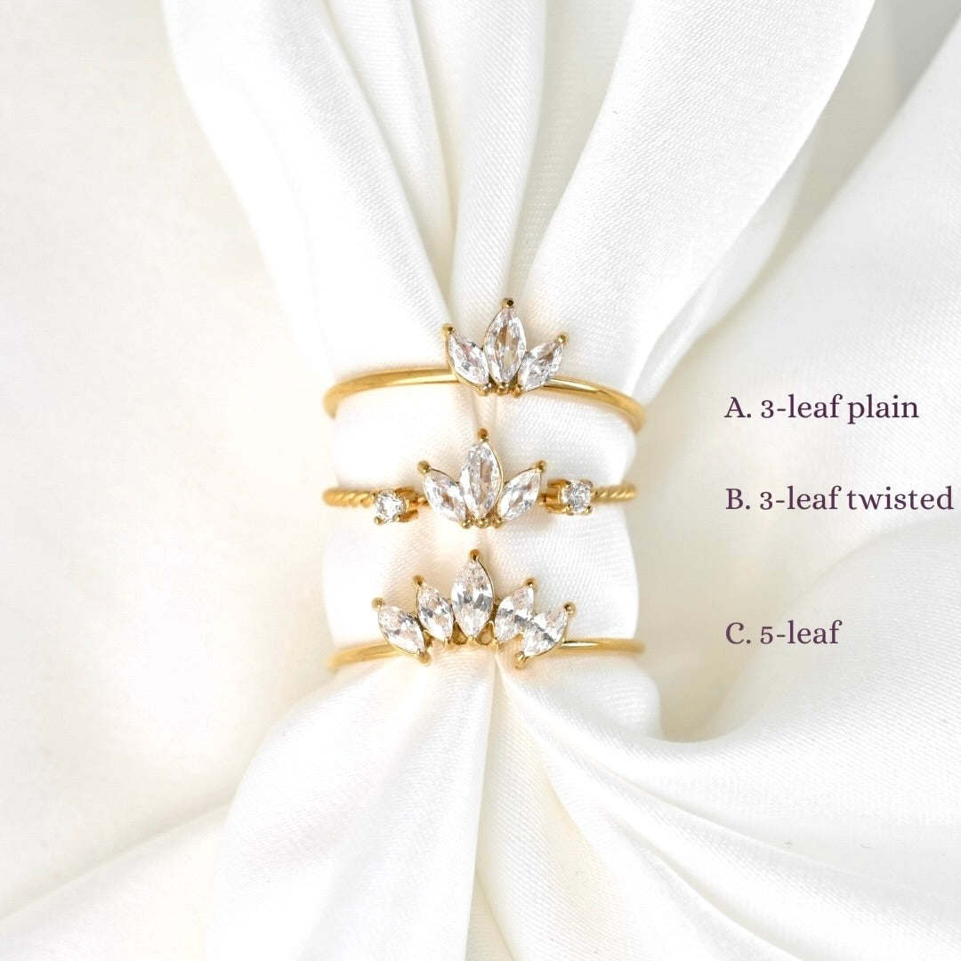 Diamond gold rings with crystal leaves on a white fabric background
