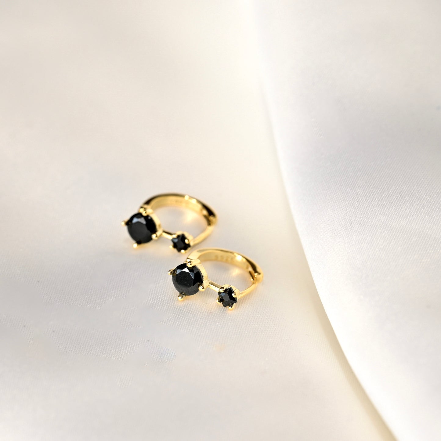 Gold earrings with black gemstones on a light background