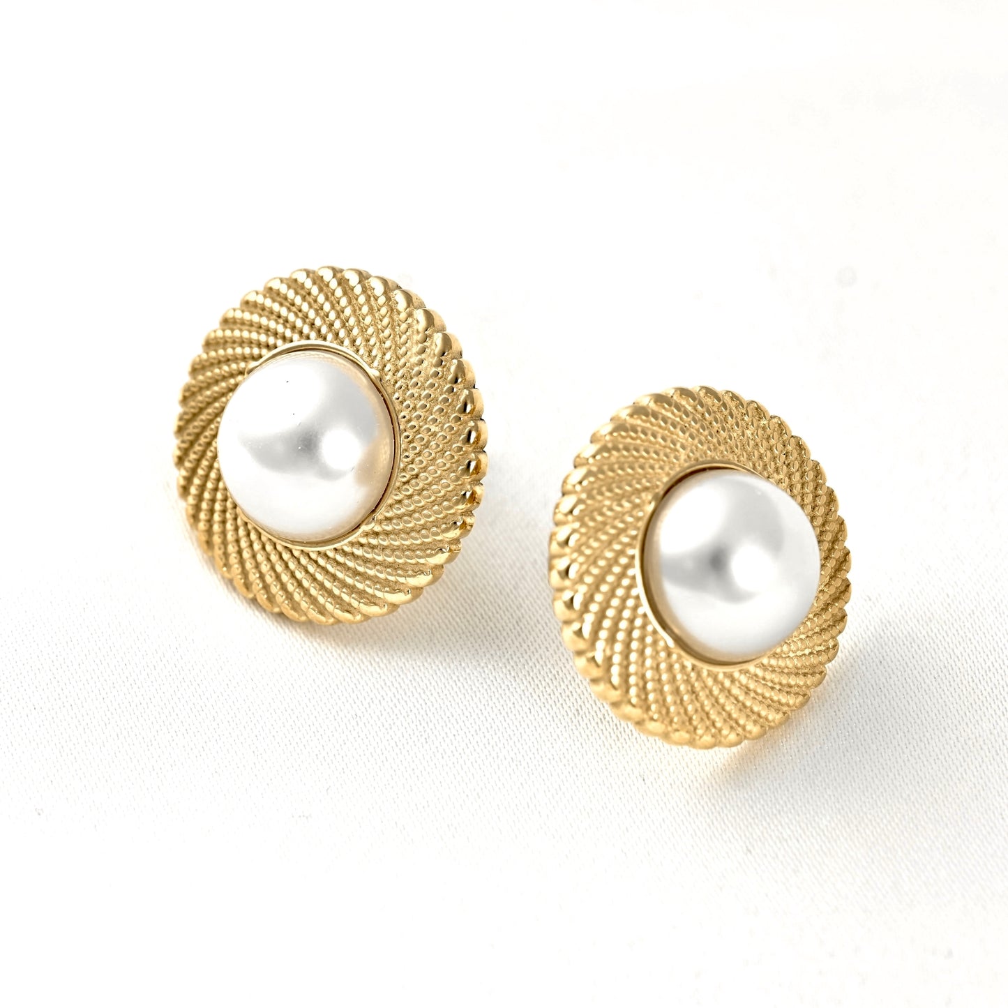 A pair of gold-toned round stud earrings with a textured rope-like border and a smooth white pearl center, shown on a clean white background.