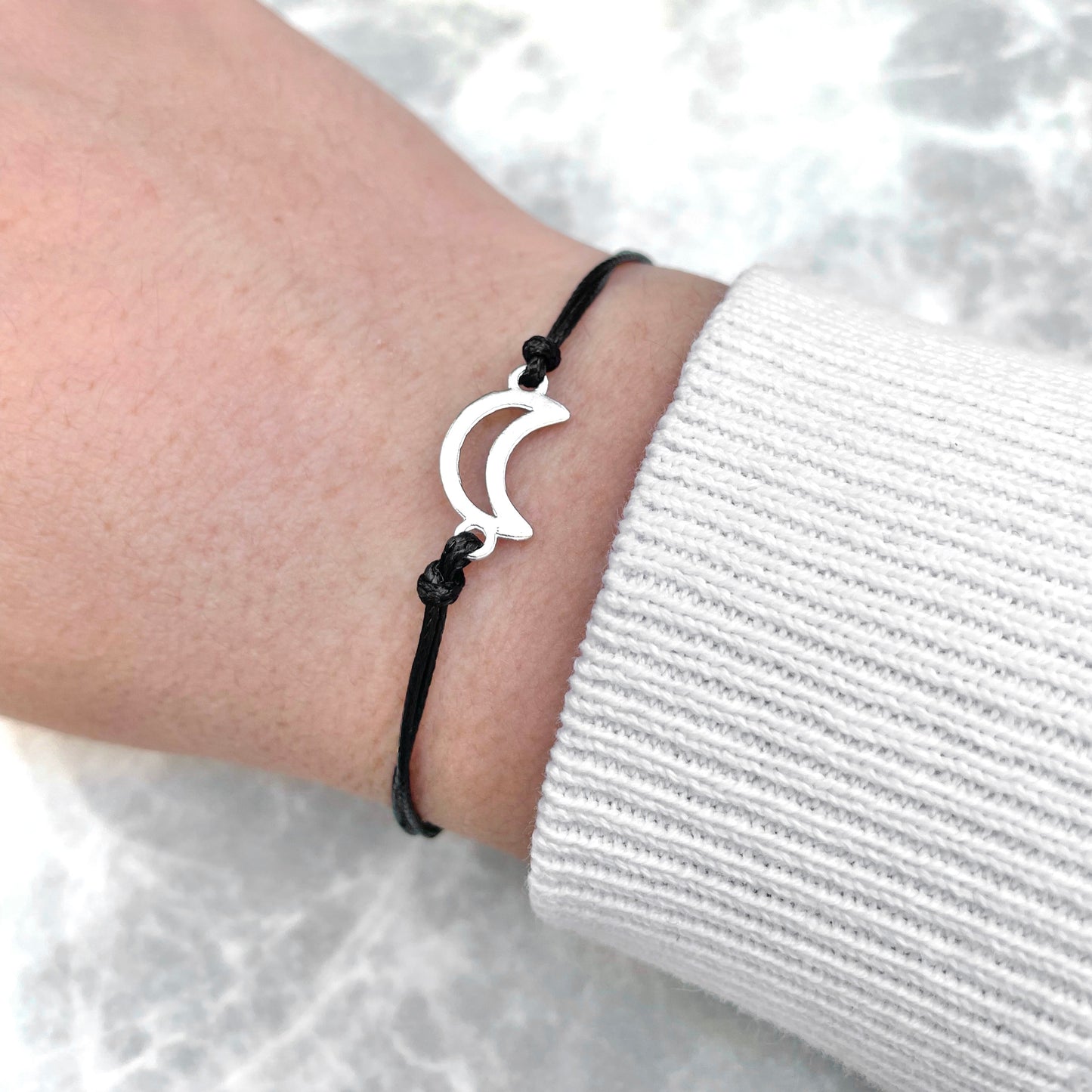 Friendship bracelet with a crescent moon  design on a wrist against a white background