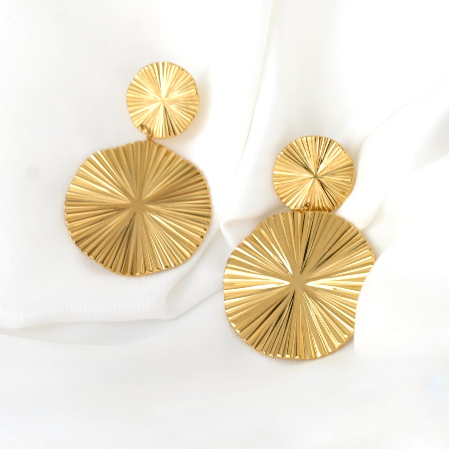 Gold circular  sun earrings on a white background