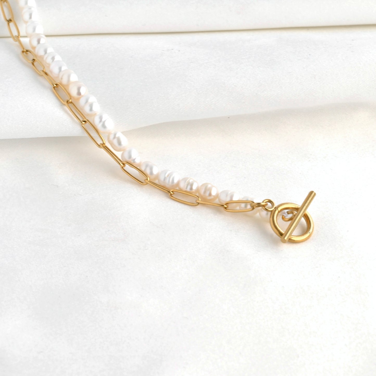 Pearl necklace with gold paperclip chain on a white background