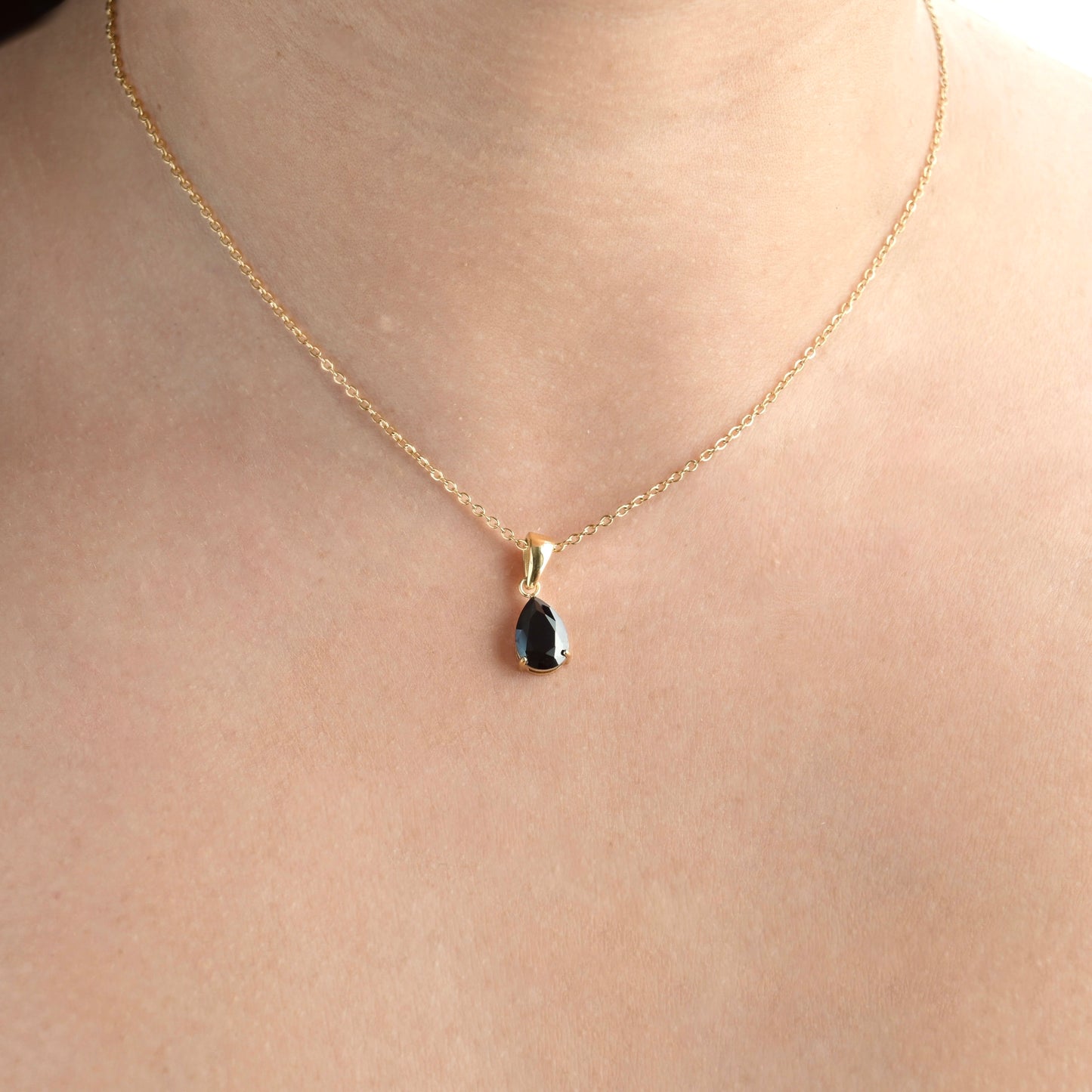 Gold Teardrop black onyx pendant on a person's neck