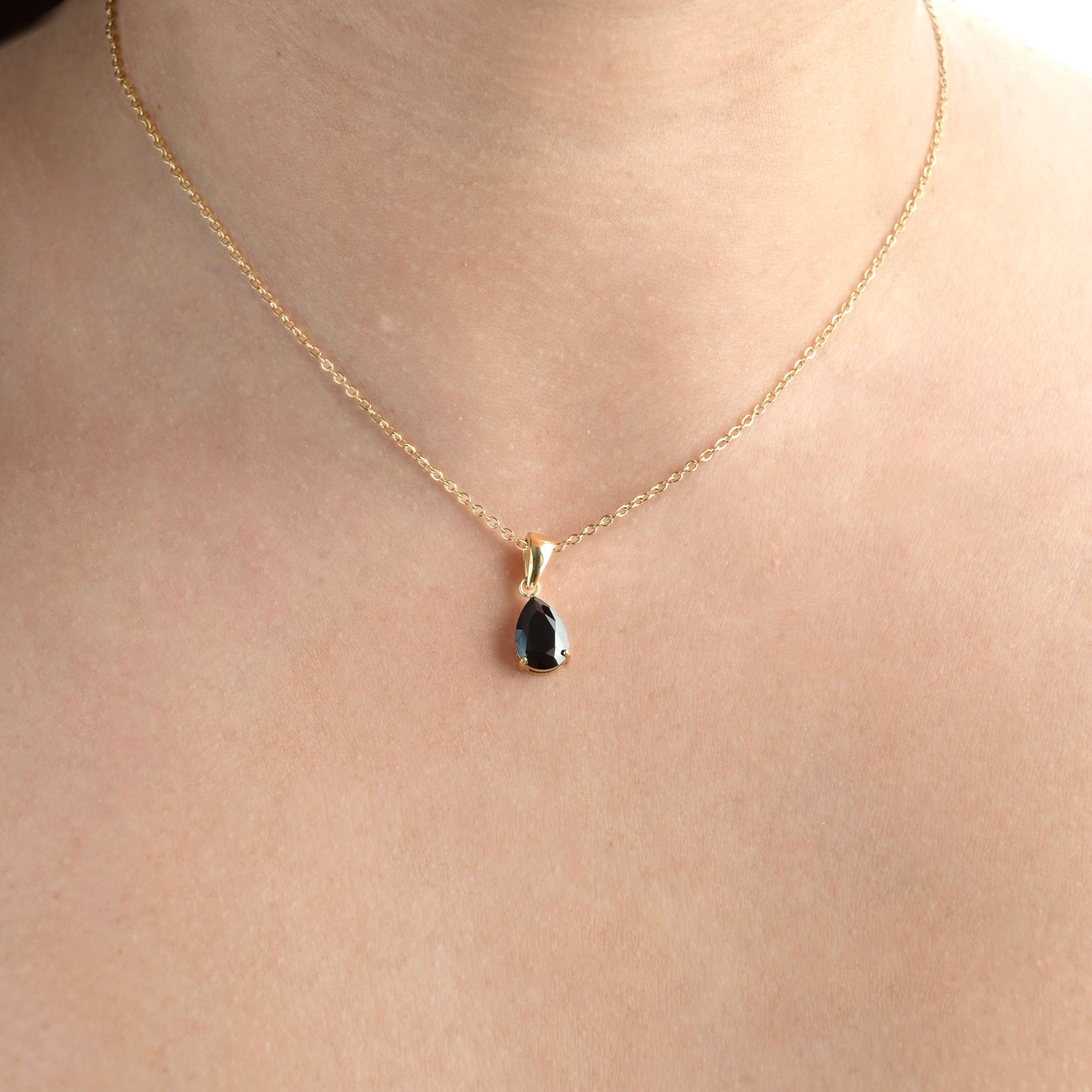 Gold Teardrop black onyx pendant on a person's neck