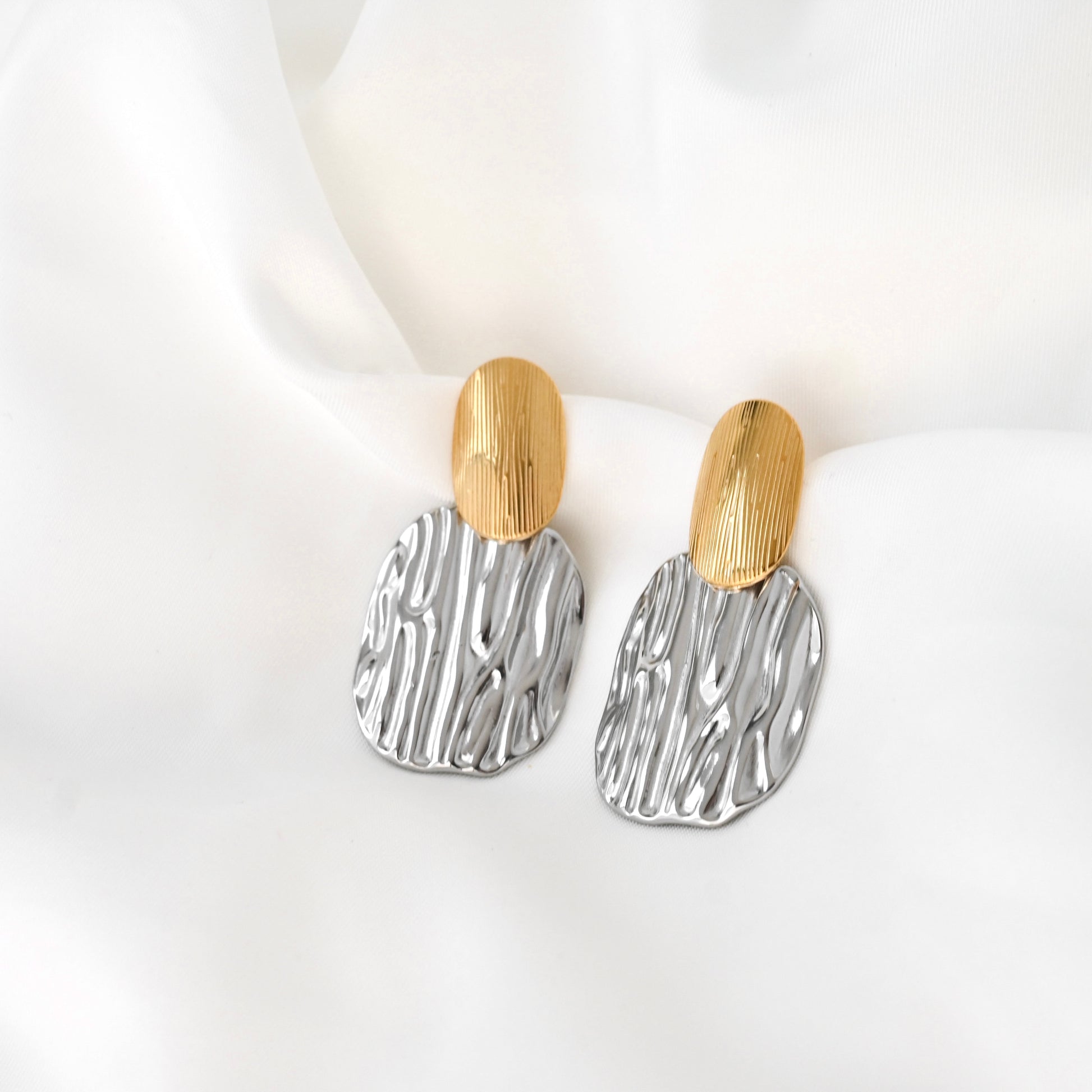 Pair of earrings with gold and silver designs on a white background