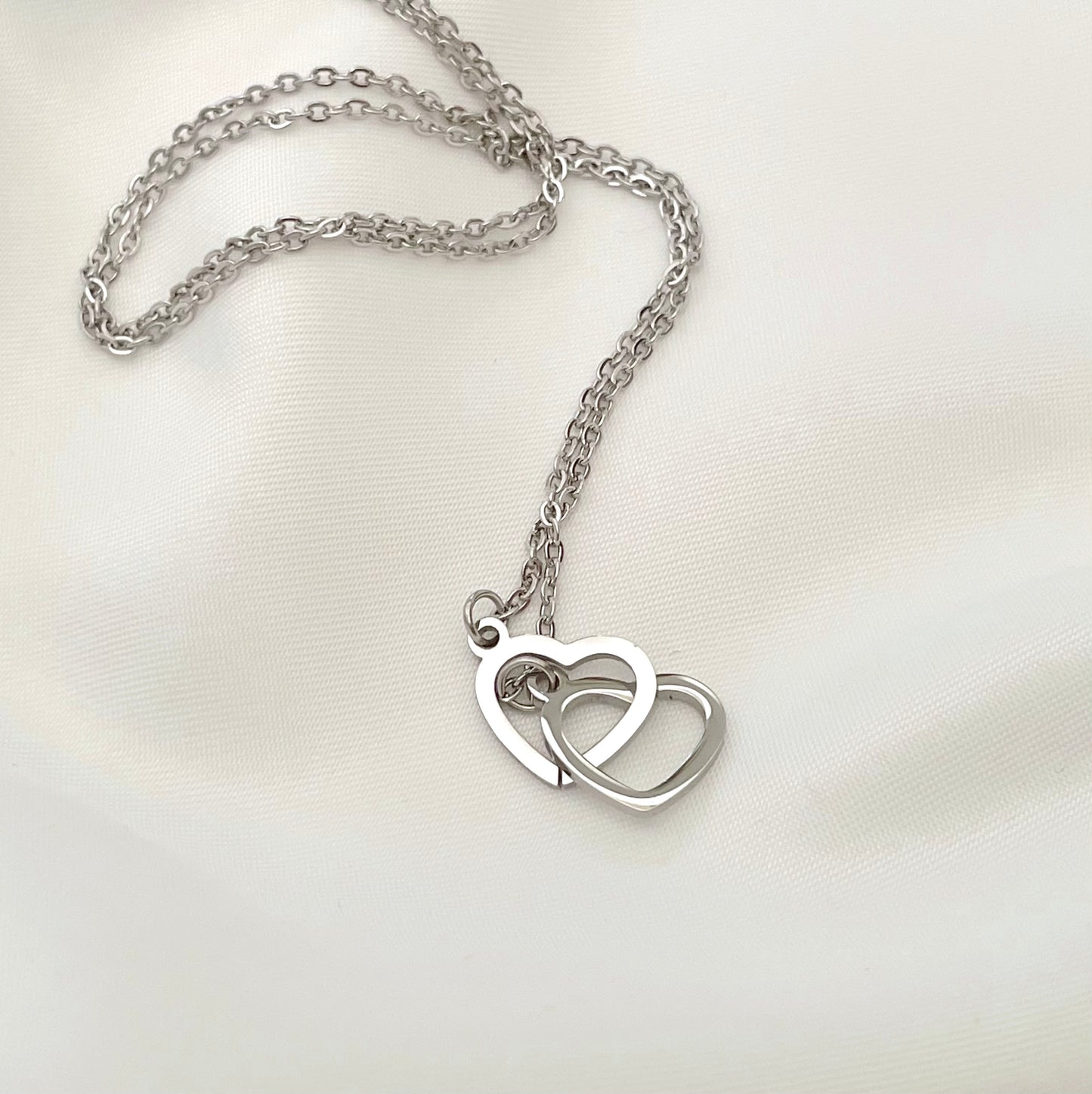 Silver necklace with a heart-shaped pendant on a white background