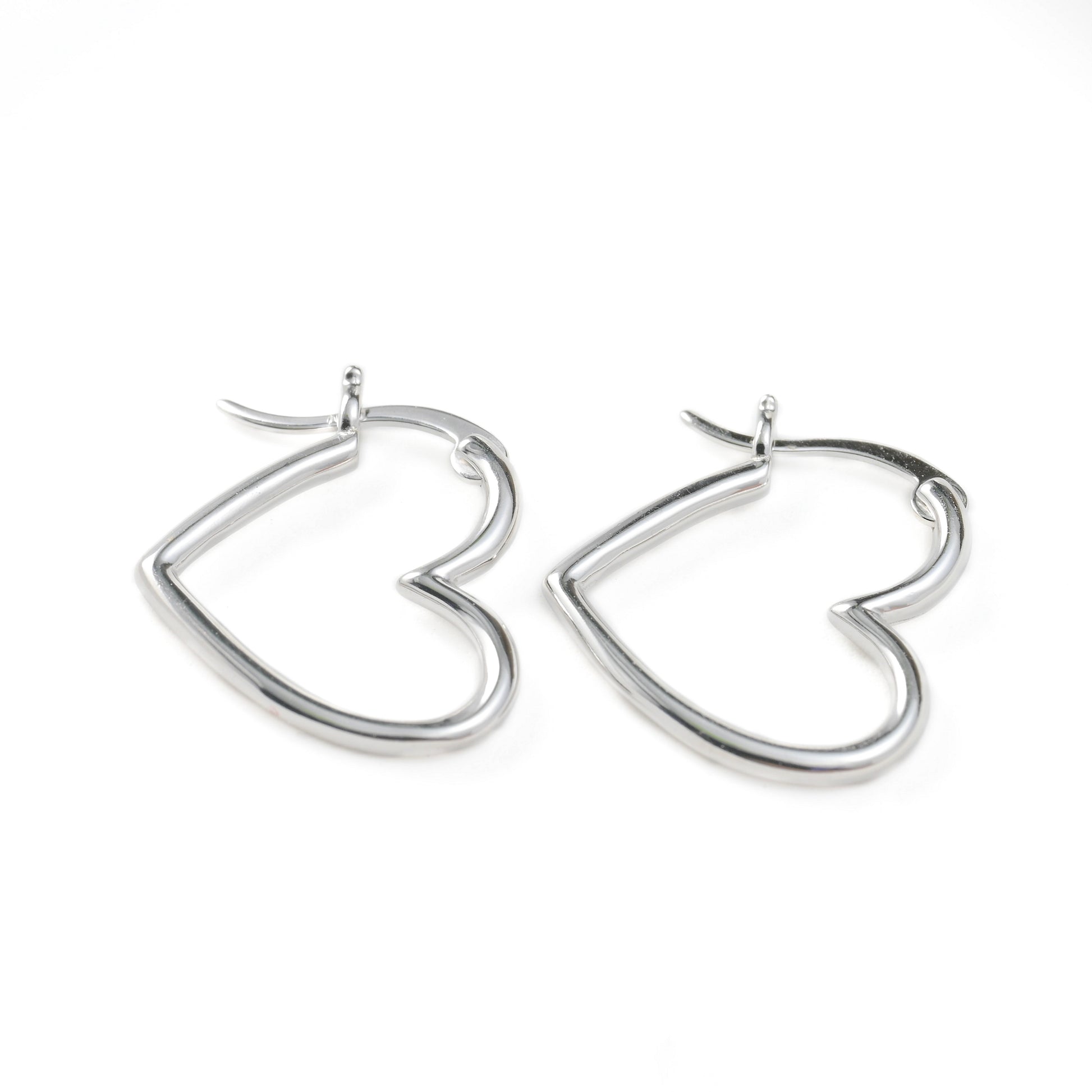 Heart-shaped silver hoop earrings on a white background