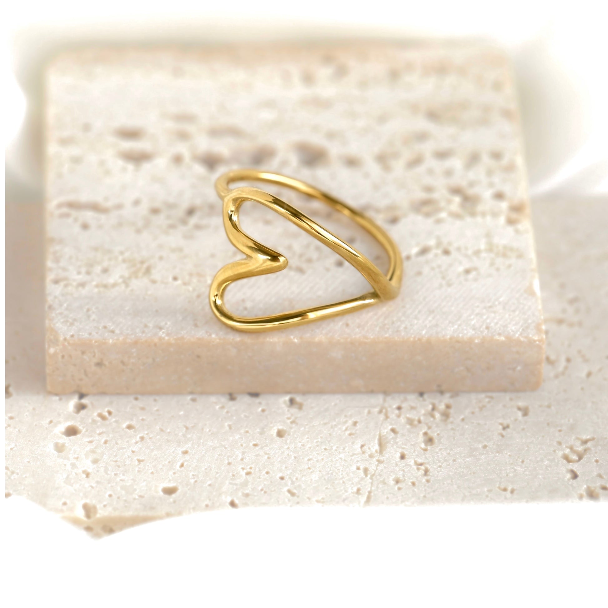 Oversized  openwork gold heart ring on a beige stone