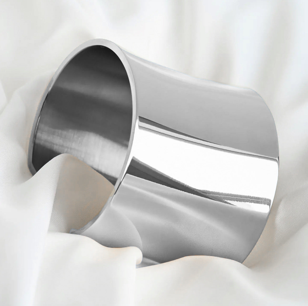 Wide silver cuff on a white fabric background