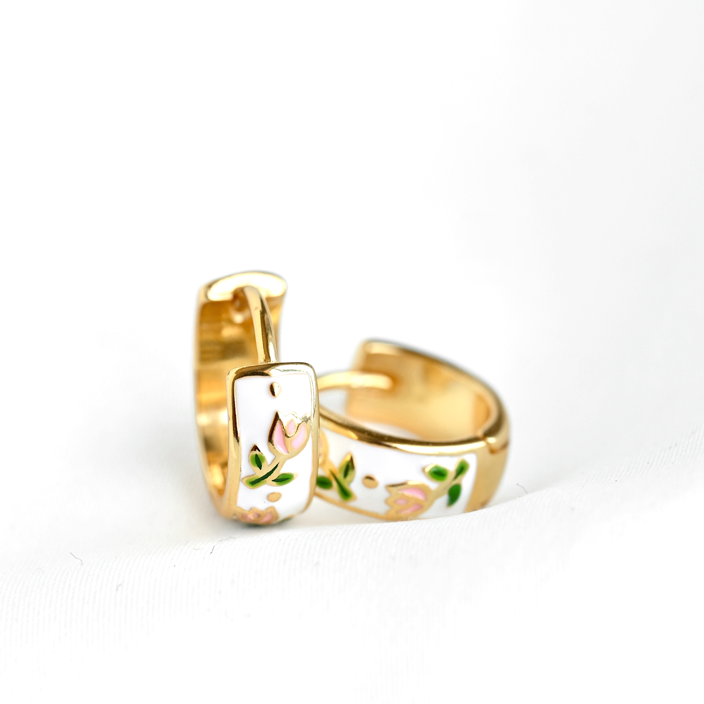 Gold hoop earrings with floral designs on a white background