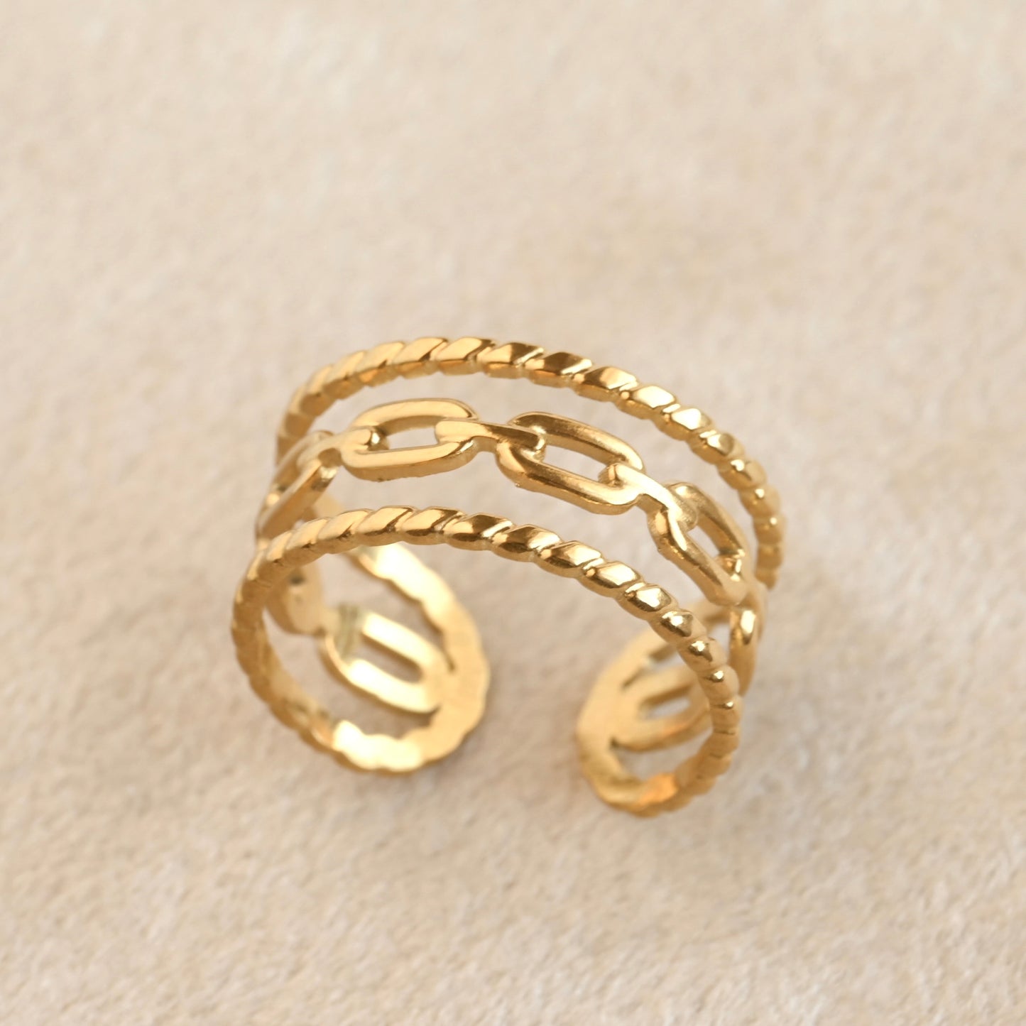 Gold ring with chain design on a beige background
