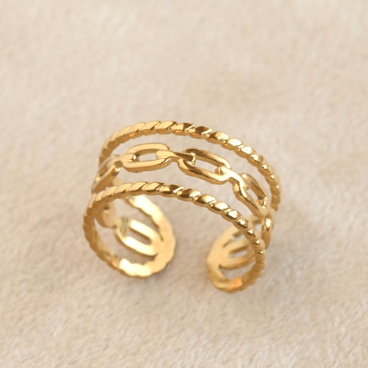 Gold ring with chain design on a beige background