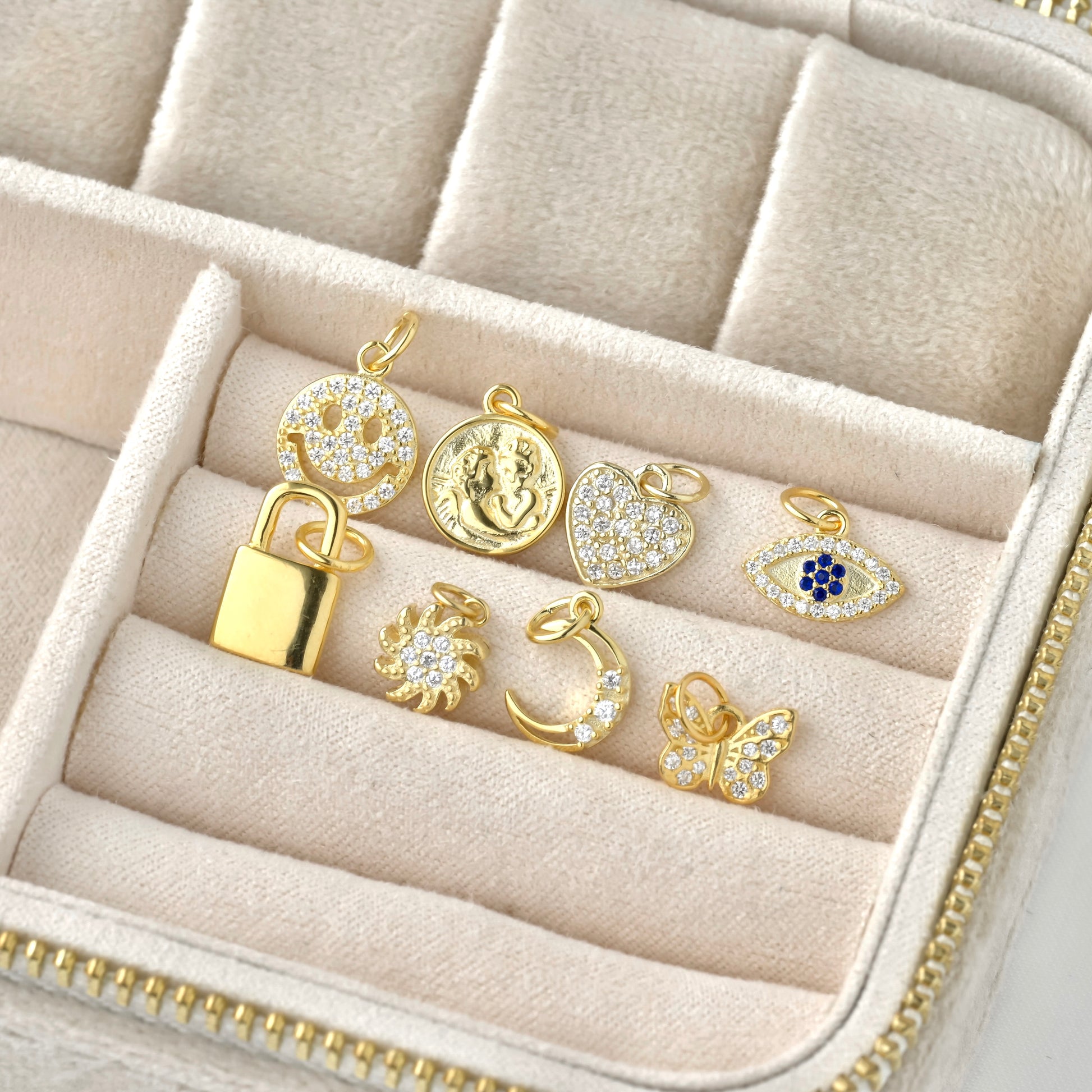 angled view: Gold pendants in a jewelry box on a beige background