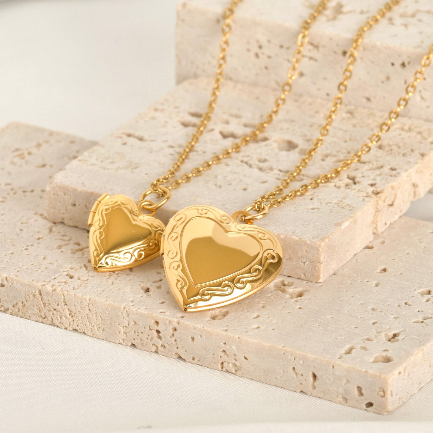 Gold heart-shaped locket necklace on a textured stone surface