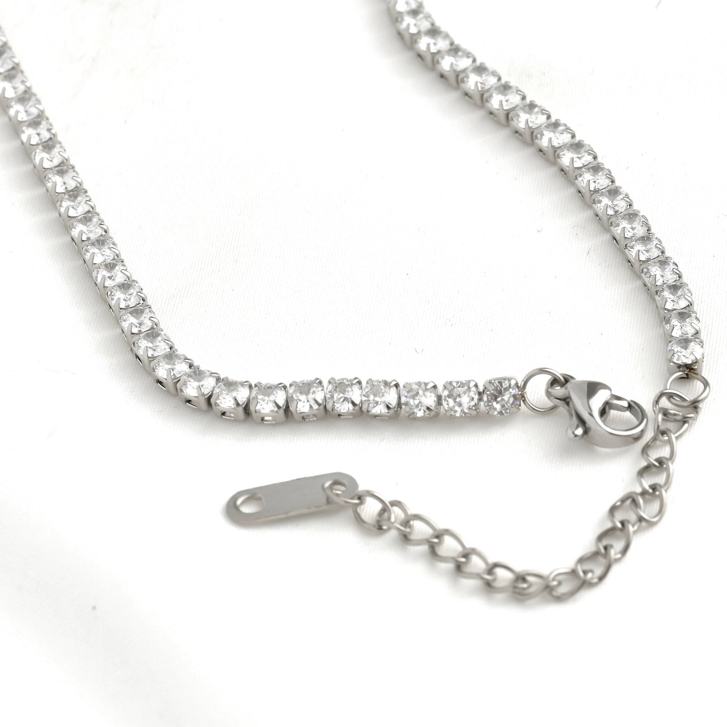 Close up view of the silver tennis necklace's lobster claw clasp and extender on a white background