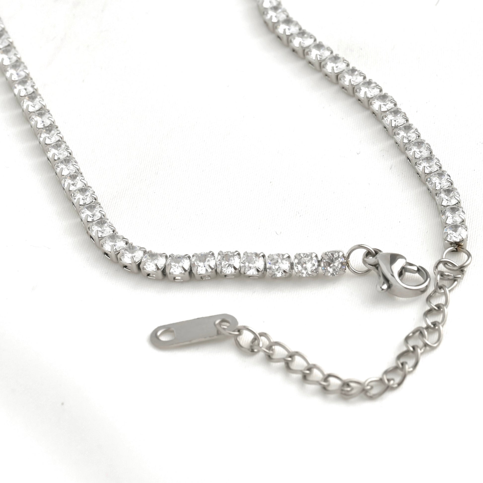 Close up view of the silver tennis necklace's lobster claw clasp and extender on a white background
