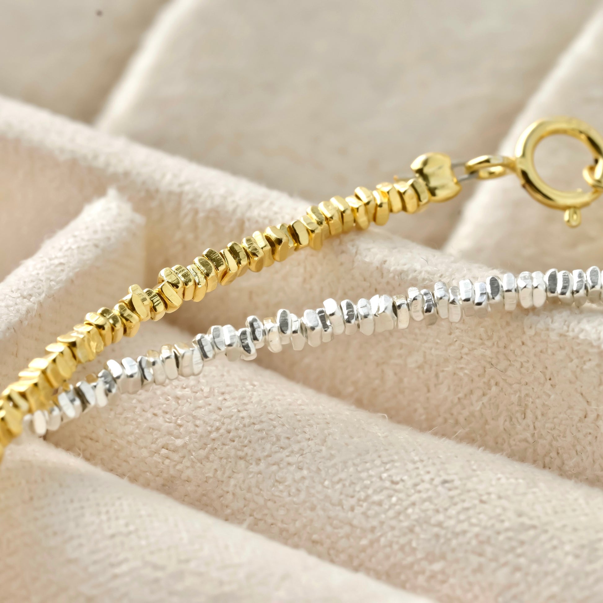 close up view of gold and silver square beads, and spring ring clasp