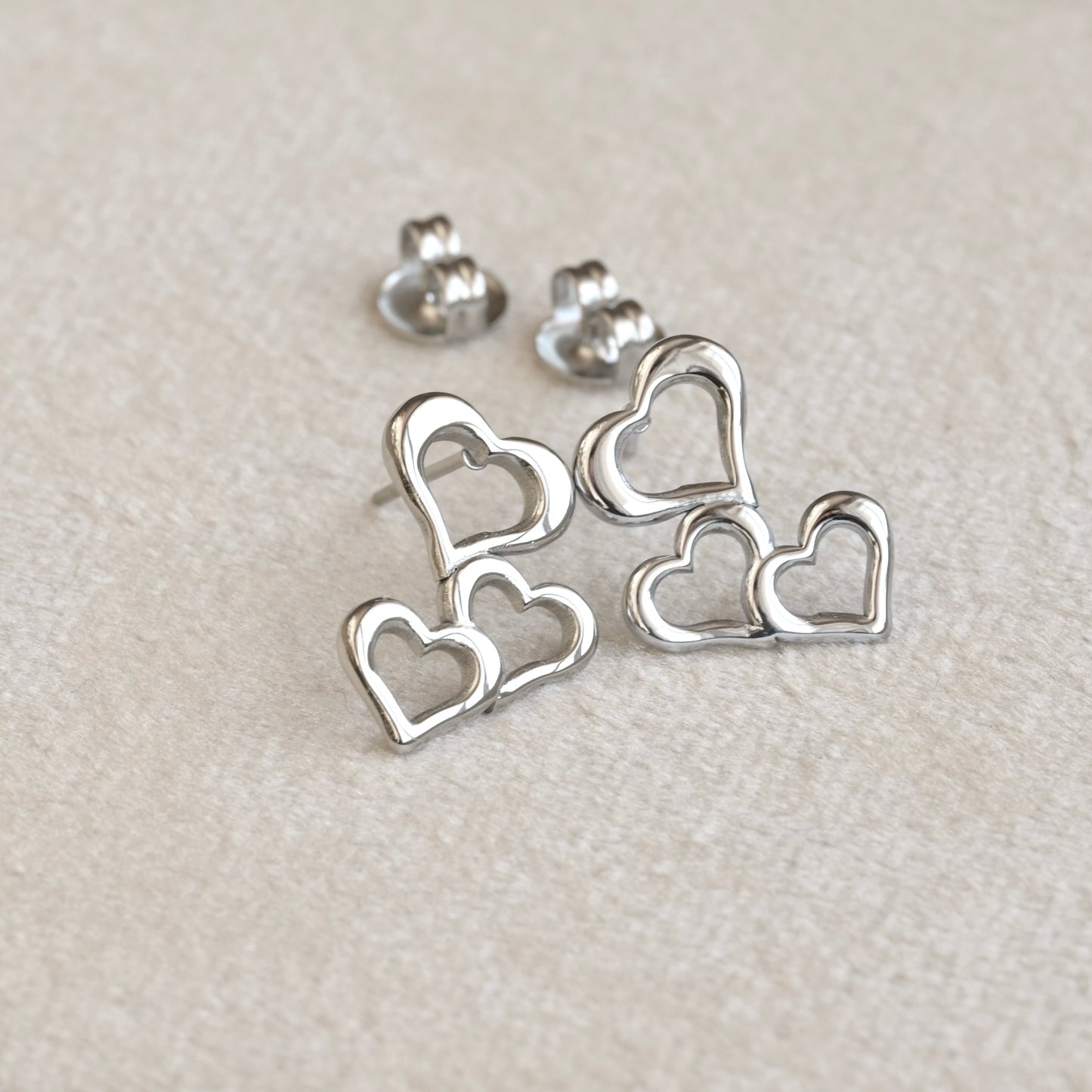 Silver heart cluster dangle earrings on a light gray background