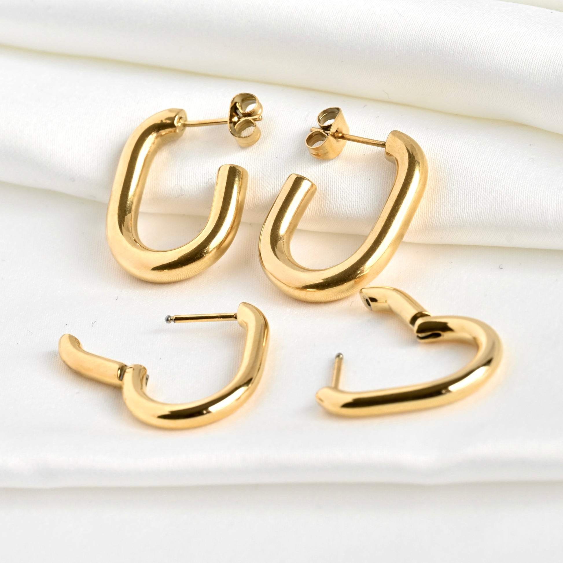 Two pairs of gold U earrings with hinged earrings are in open position to illustrate the clicker closure