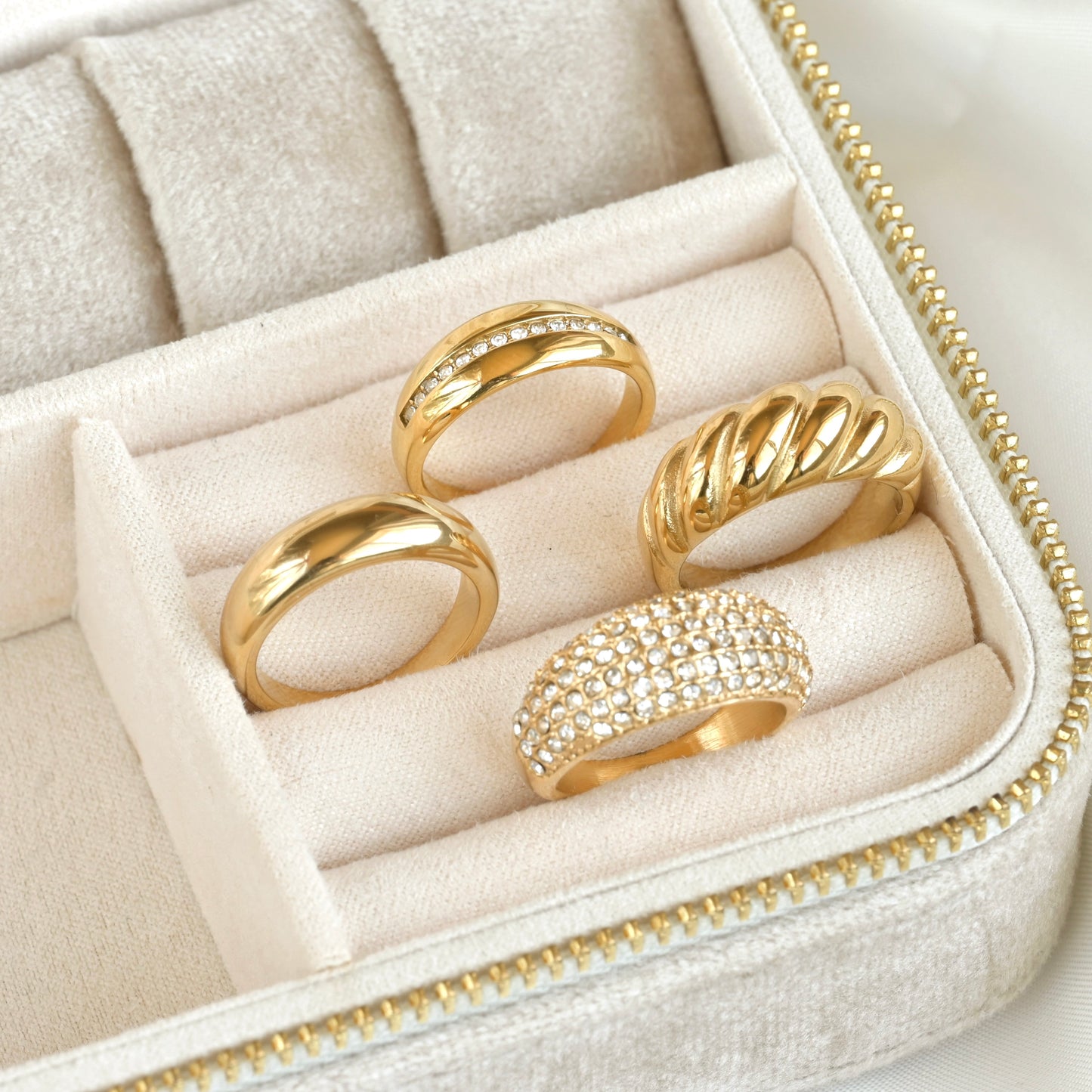 Set of thick gold statement rings, two of them with CZ accents in a jewelry box on a light background
